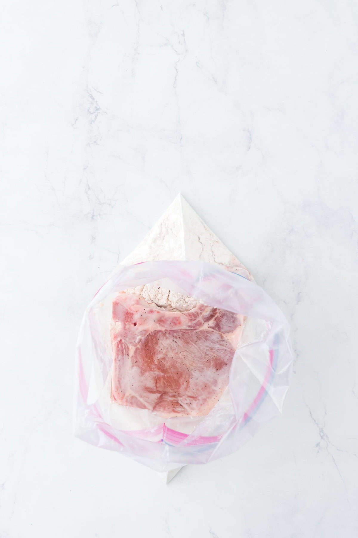 Marinated pork chops in seasoned flour in a ziptop bag