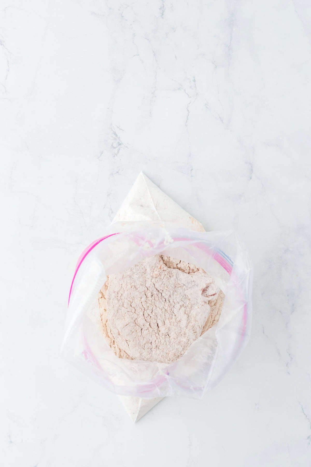 Dredged pork chops in a seasoned flour inside a ziptop bag