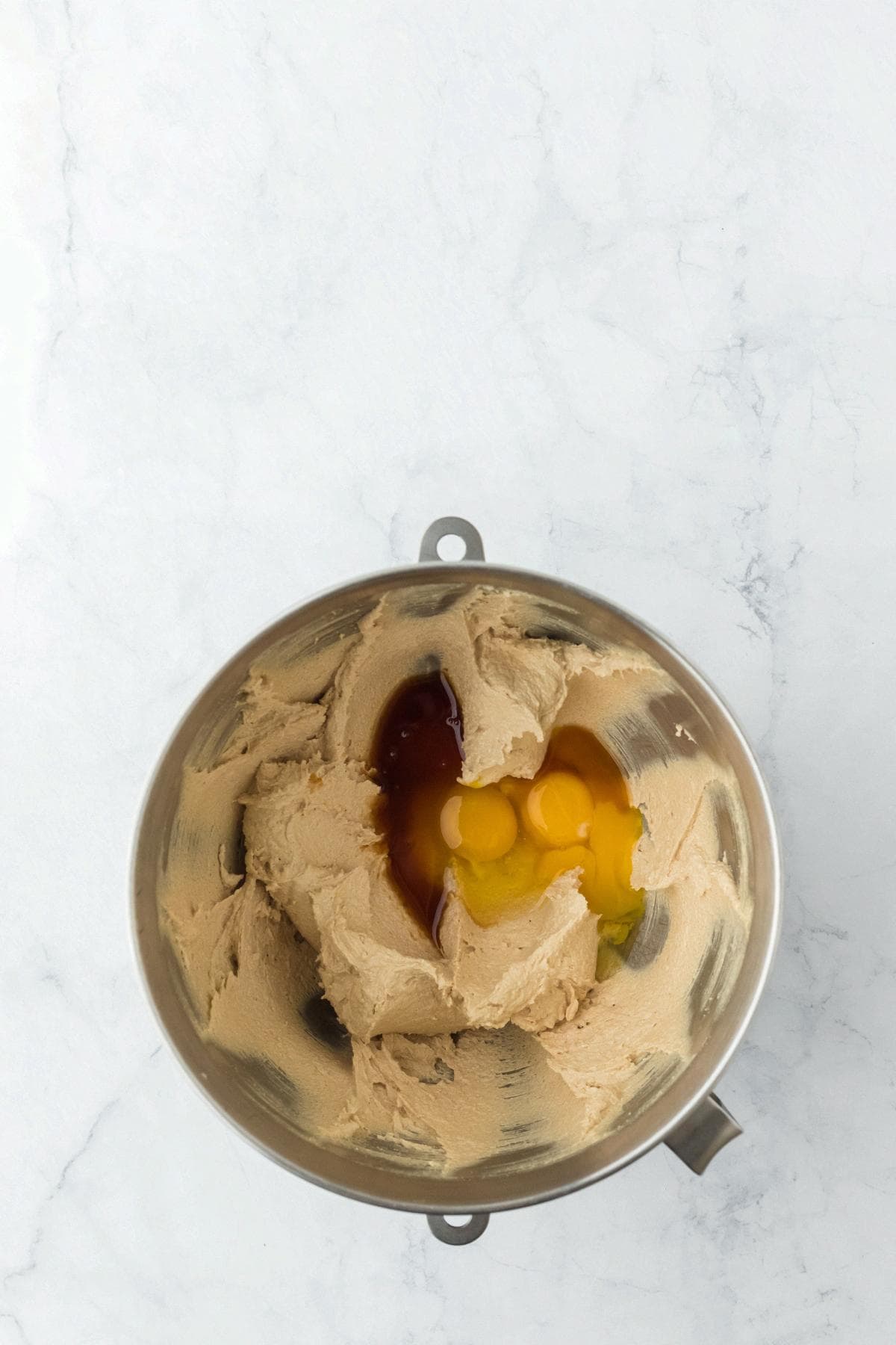 Cookie dough in a mixer bowl with eggs and vanilla added