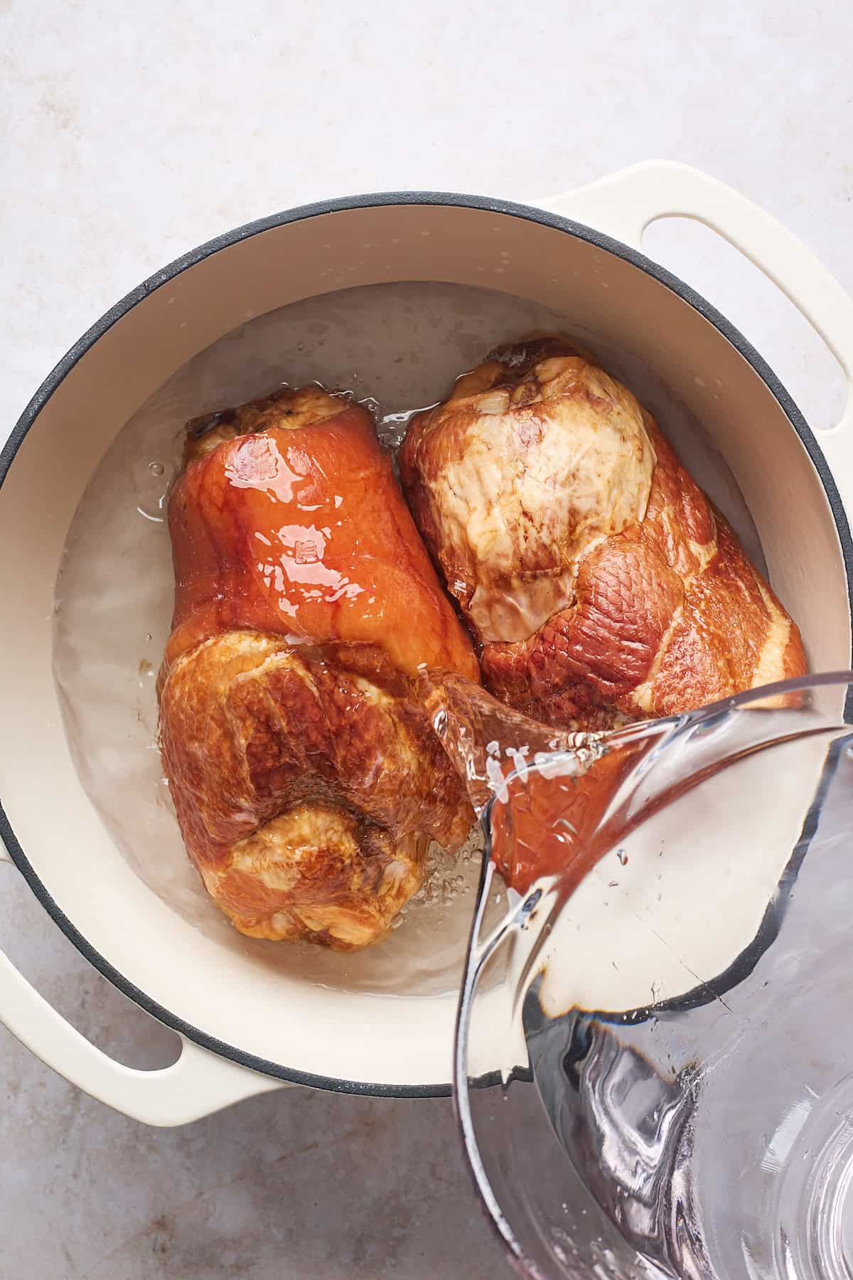 Water adding to pot with smoked turkey necks in a white pot