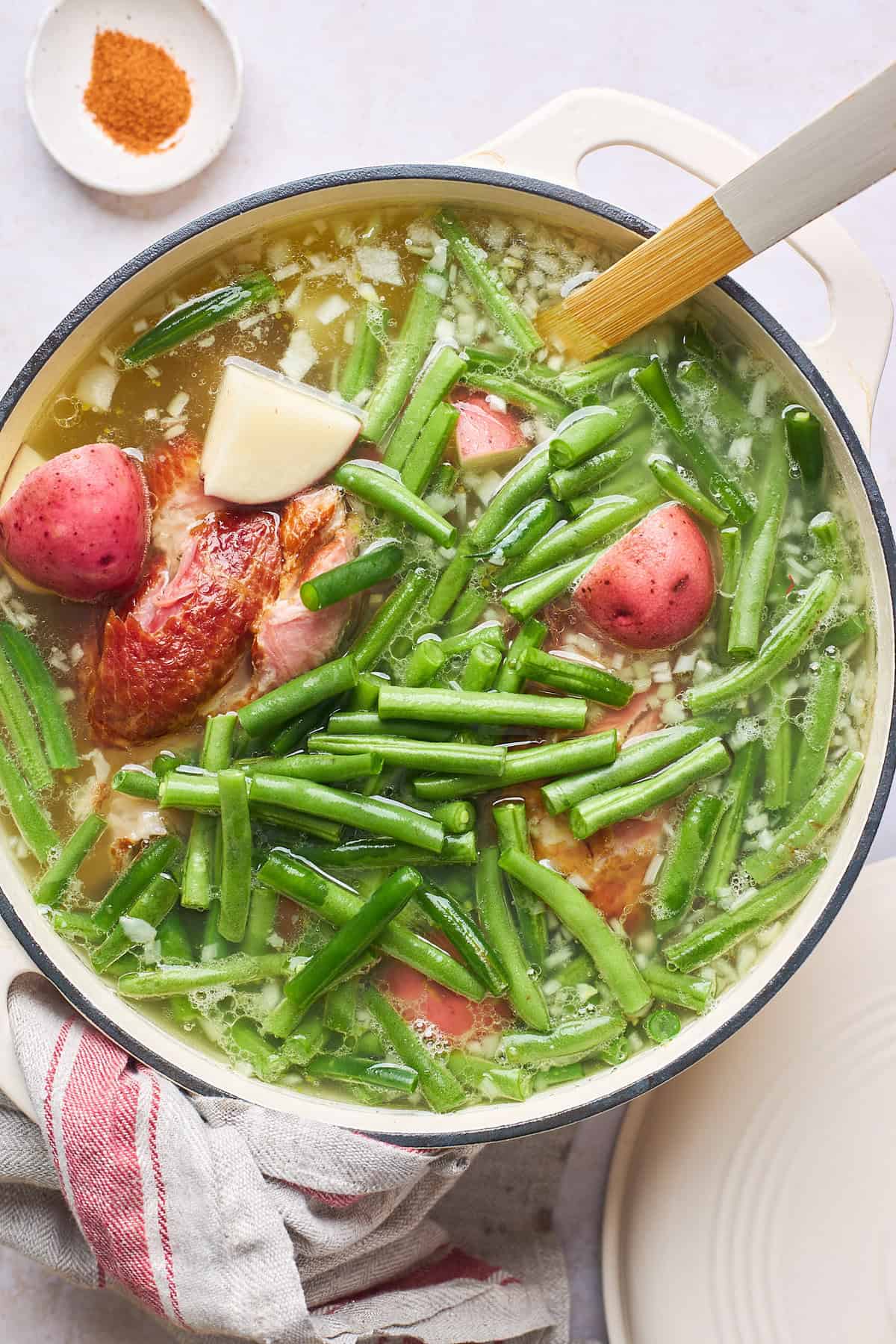 Green beans and potatoes along with smoked turkey in a large pot stirring together