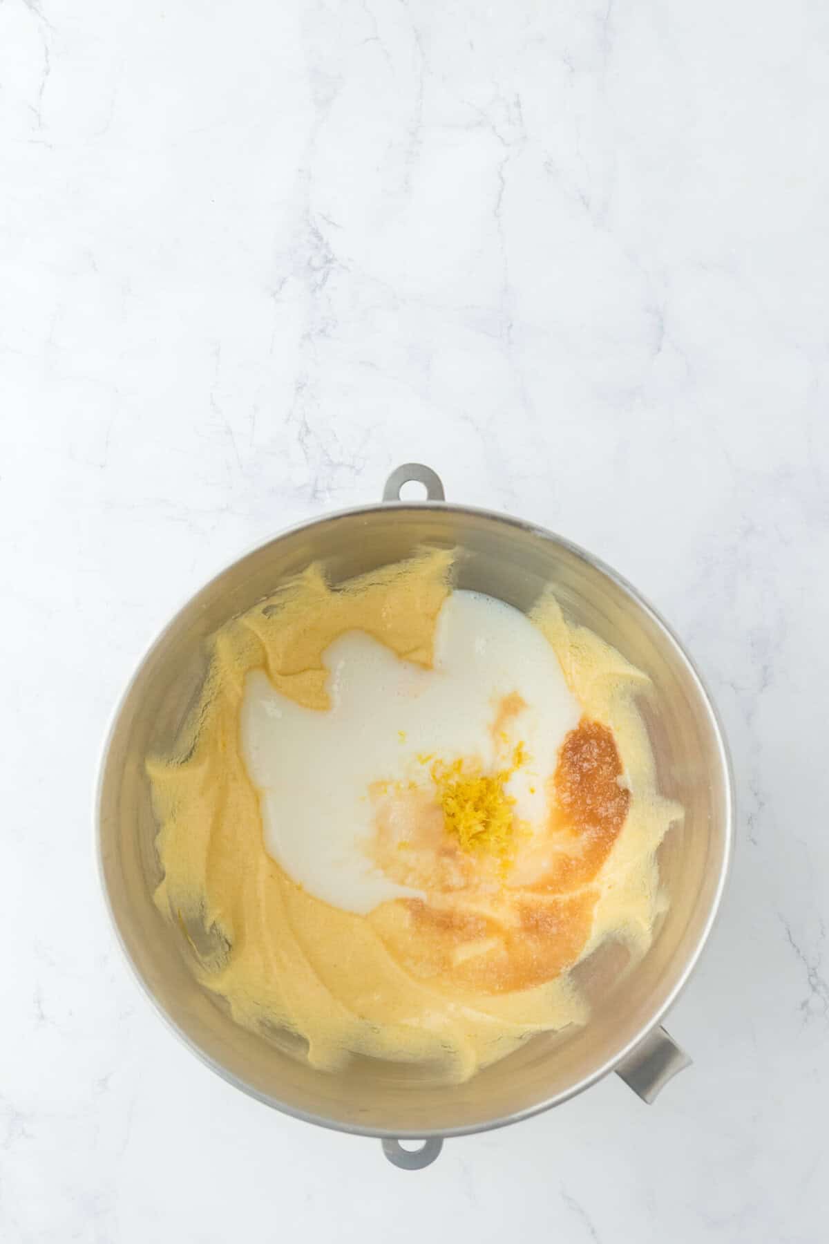 Buttermilk and vanilla being added to a final chess pie recipe filling in a mixing bowl on white background