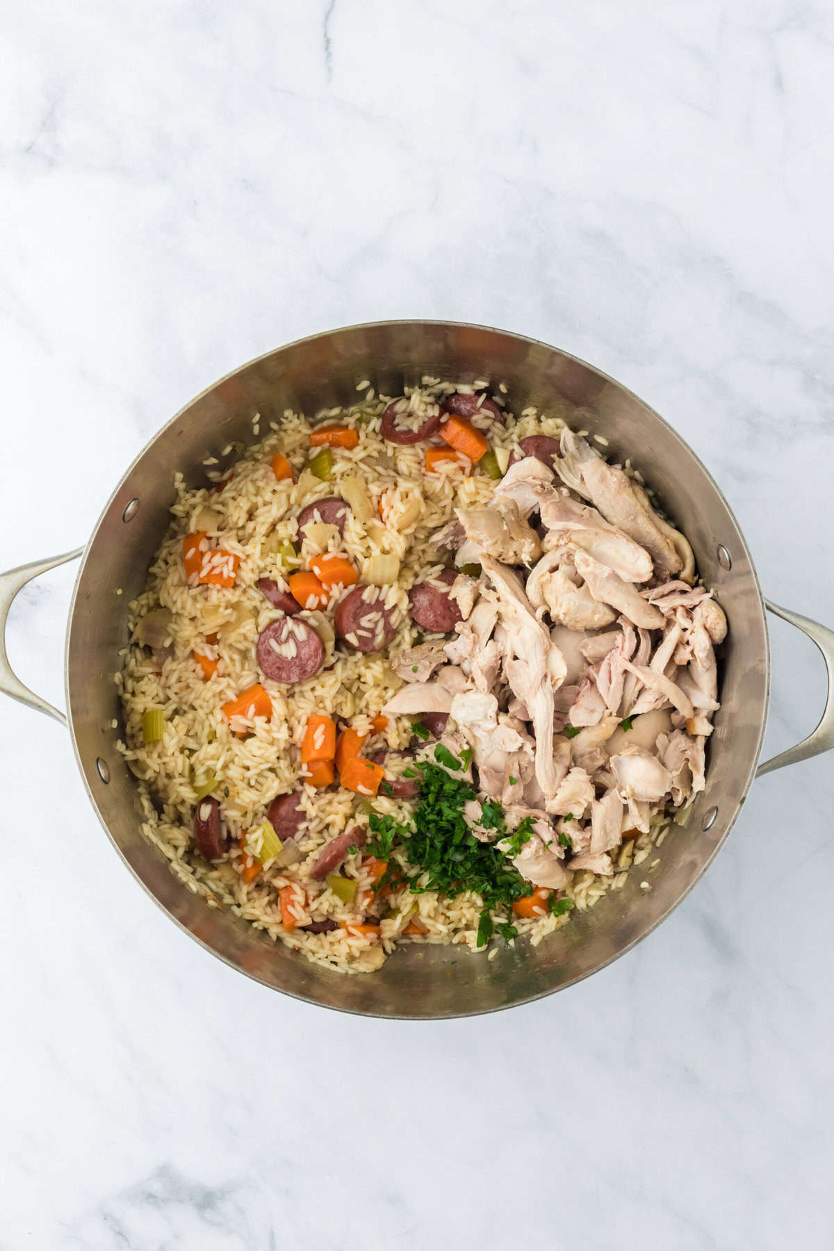 Shredded chicken added back into the chicken bog pot on a white background