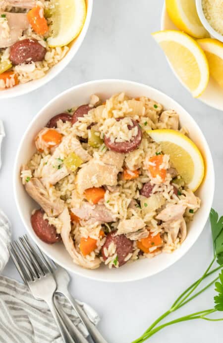 A large white bowl filled with chicken bog with a fork on the side in on a white background