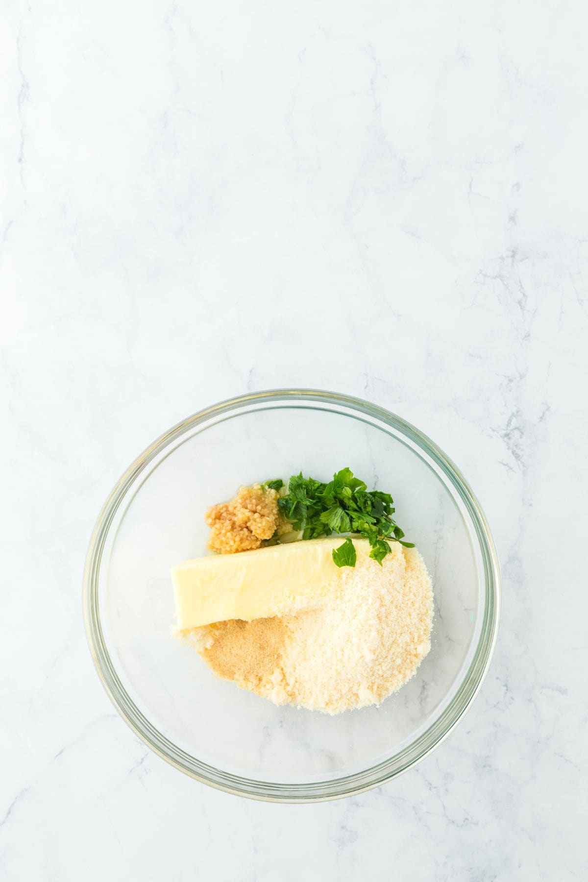 A mixing bowl containing the ingredients to make garlic bread, ready to be mixed