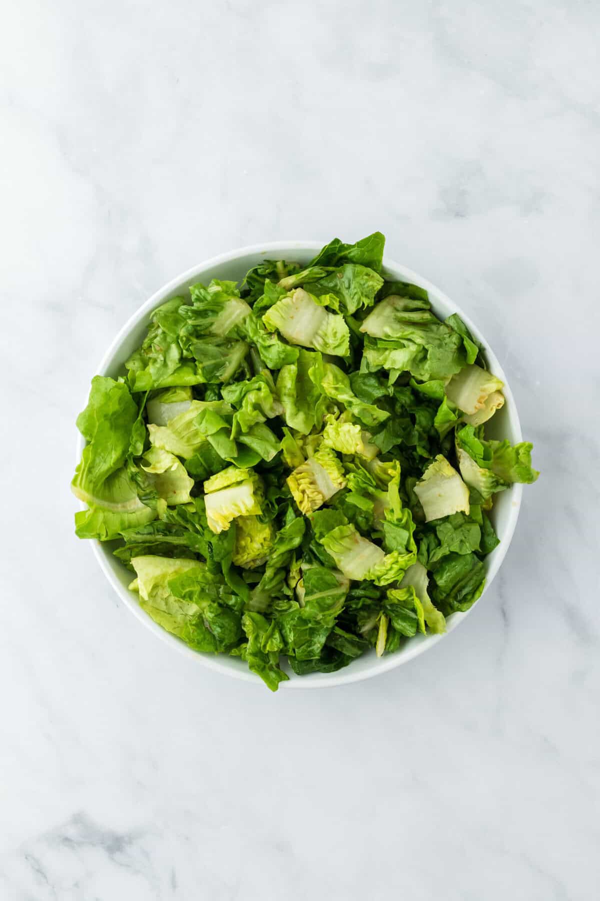 Dressed lettuce on a white bowl on a white background