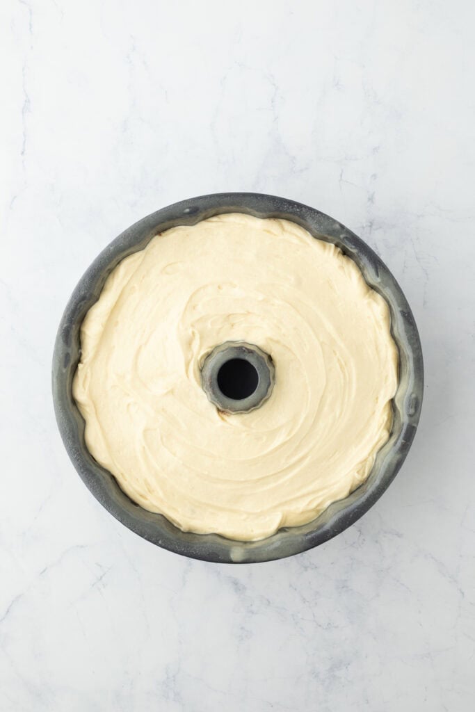 Remaining batter added to bundt pan on white background