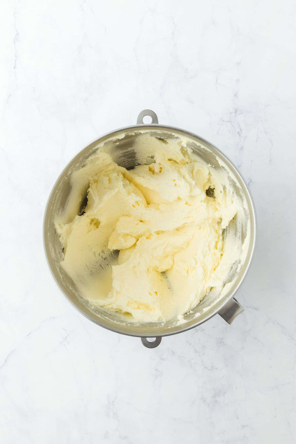 Butter and sugar creamed in a stand mixer until light and fluffy on white background