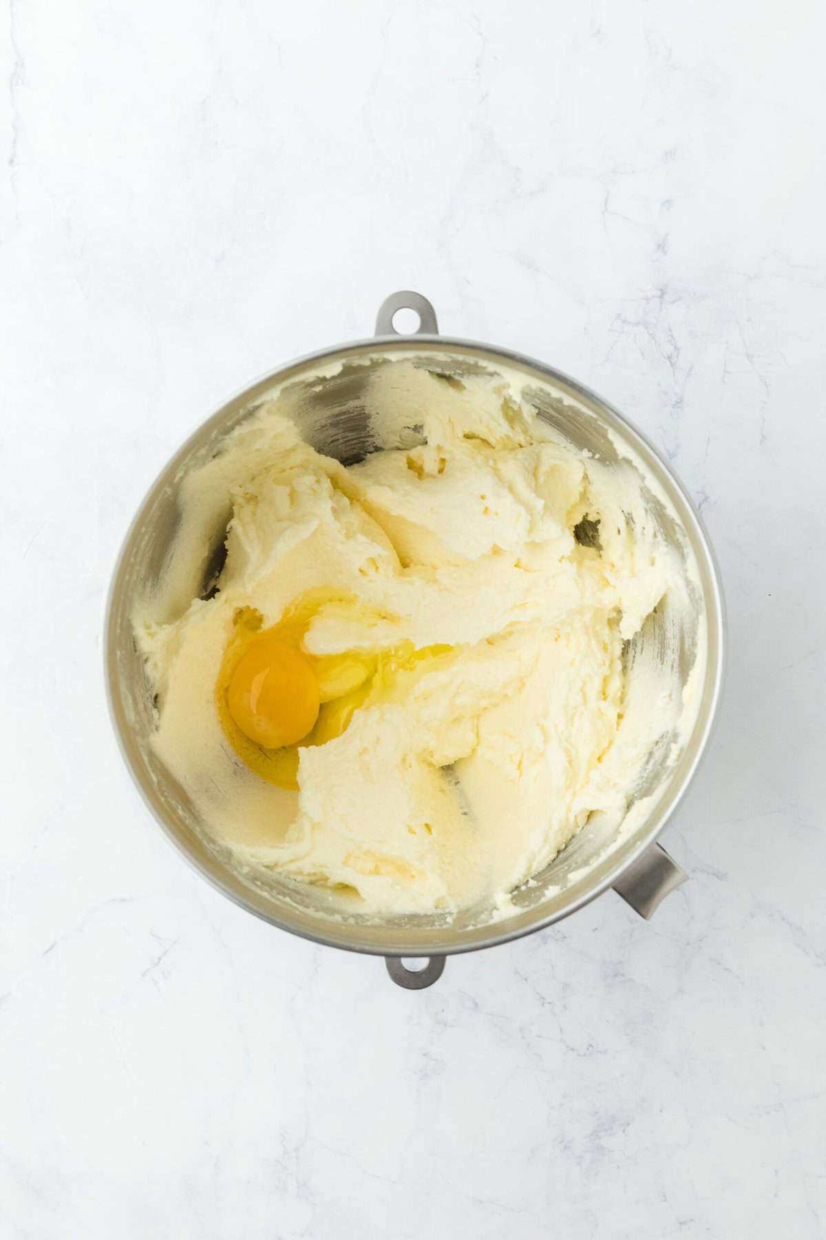 Eggs added to cake mixture in stand mixer bowl on white background