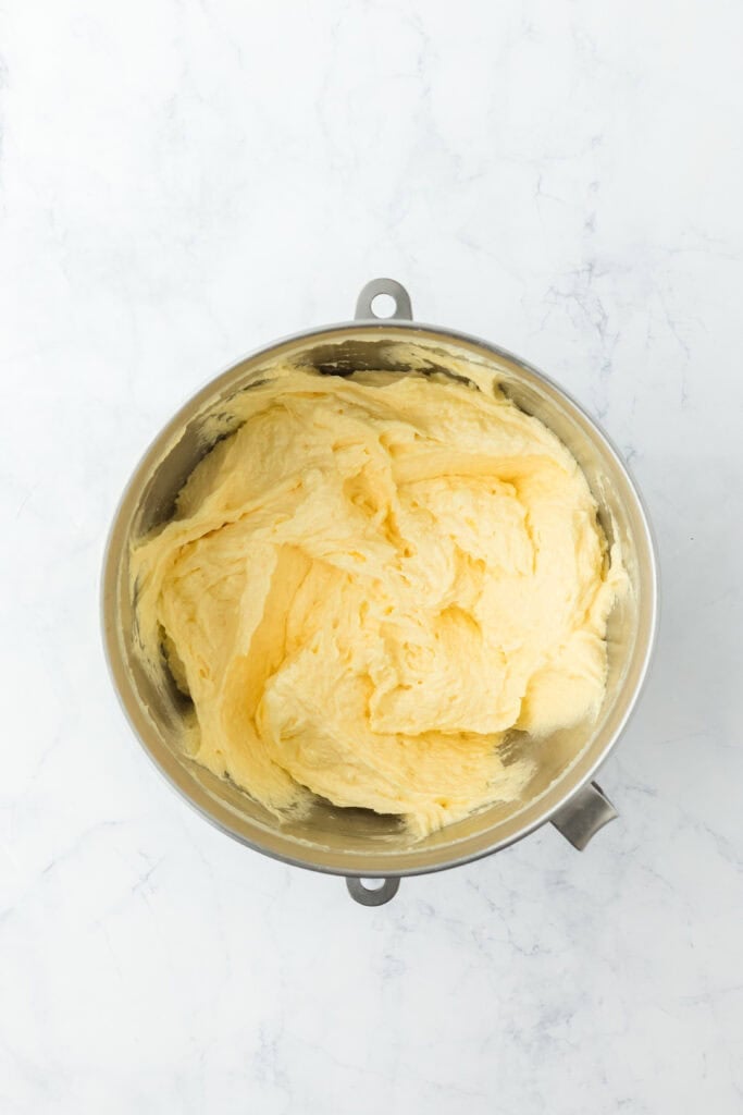 Eggs, butter and sugar creamed in a mixer bowl on white background