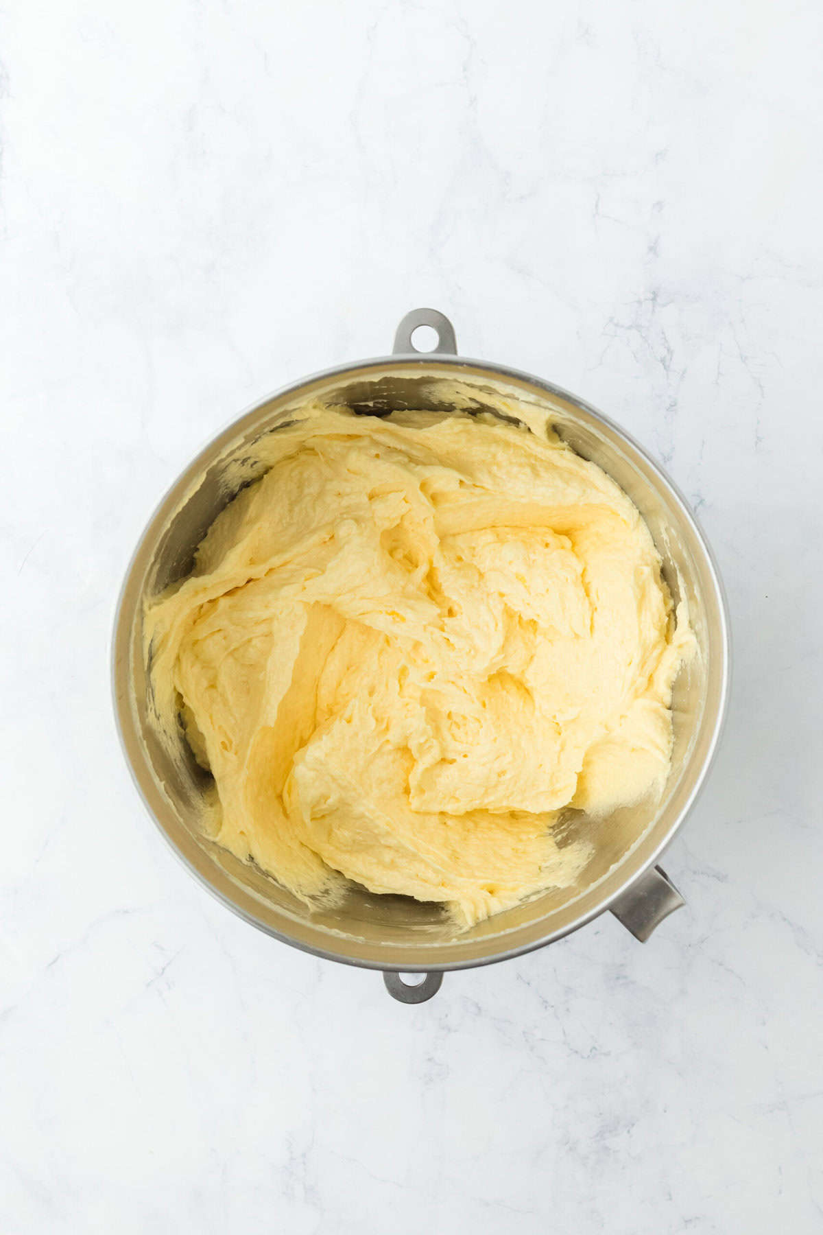 Eggs, butter and sugar creamed in a mixer bowl on white background