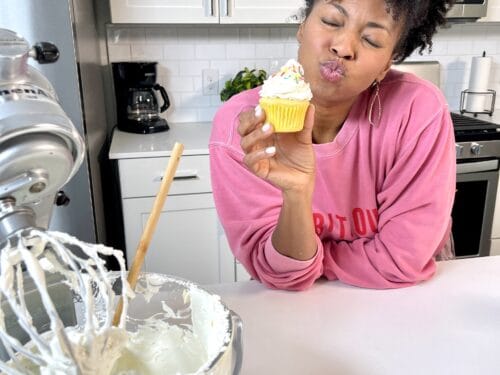 Jocelyn Delk Adams holding a cupcake with swiss meringue buttercream on it next to a stand mixer