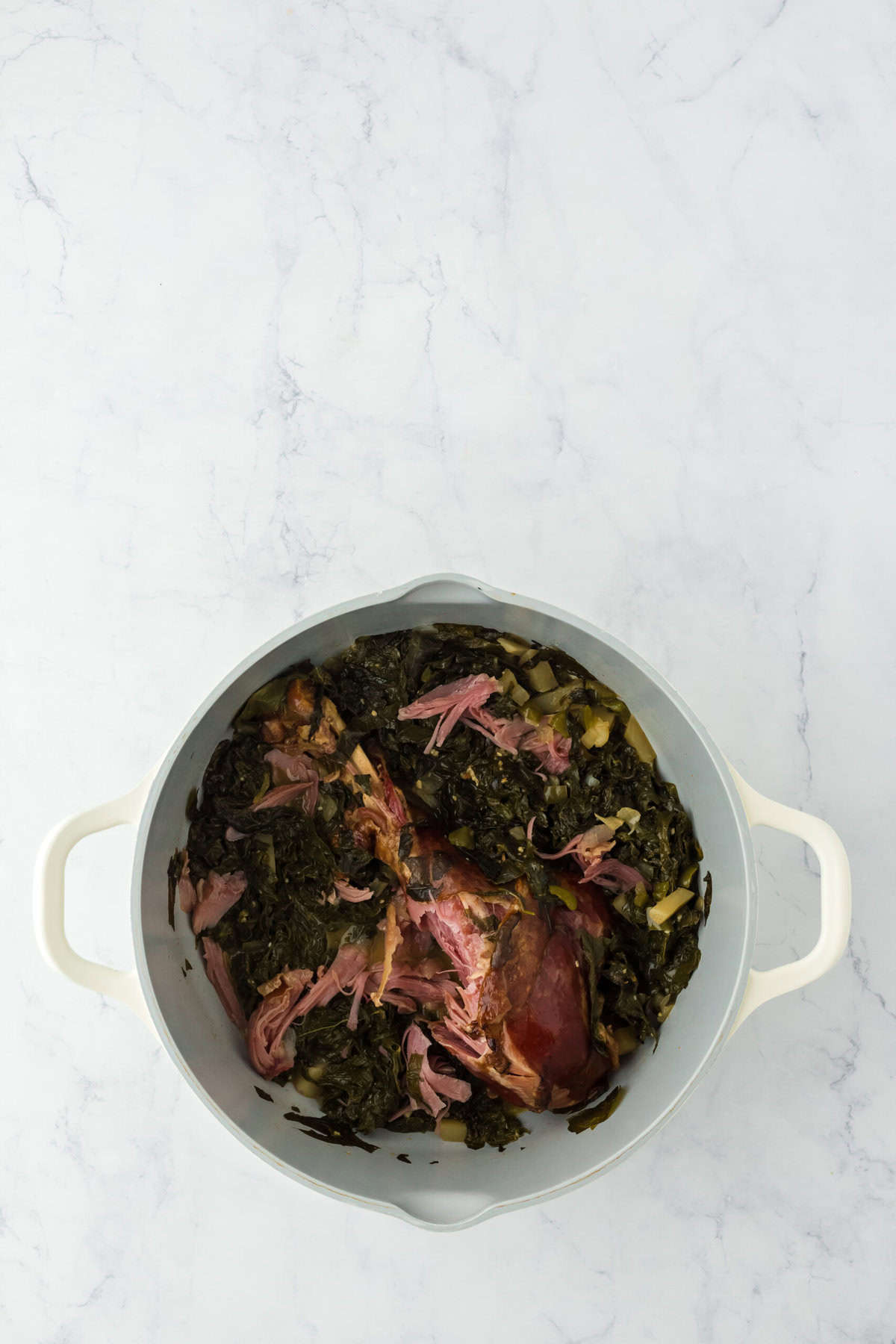 Turnip greens finished in a large pot with turkey shredded on white background