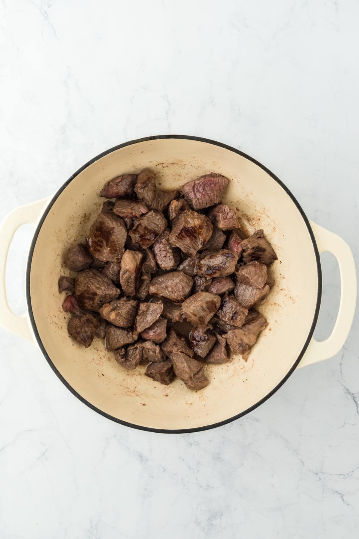 Seared beef chunks browned on all sides inside the braiser