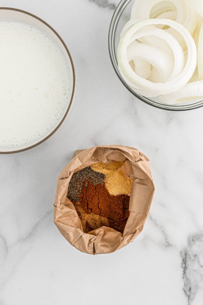 Several spices and cornmeal in a paper bag on countertop
