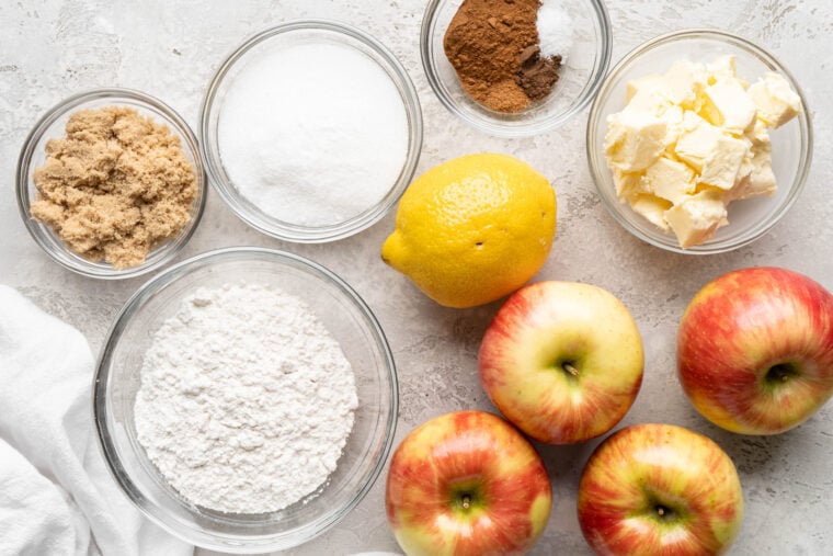 Ingredients needed to make brown apple betty recipe in clear bowls on gray background