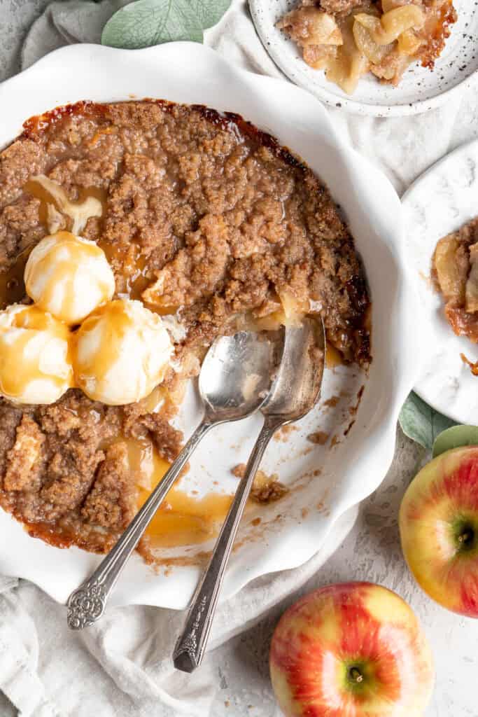 An apple brown betty recipe dug into with vanilla ice cream on top