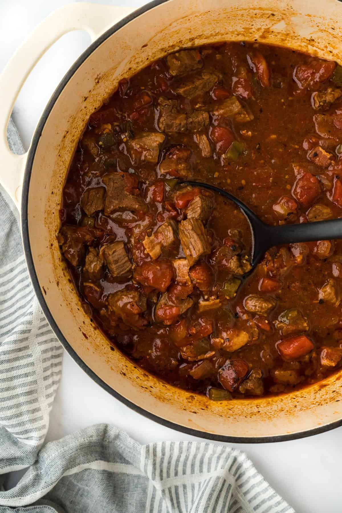 Brisket chili in a Dutch oven, showing the rich, chunky stew with a ladle inside