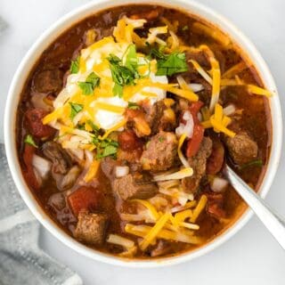 Overhead shot of a bowl of brisket chili topped with shredded cheese, sour cream, and cilantro