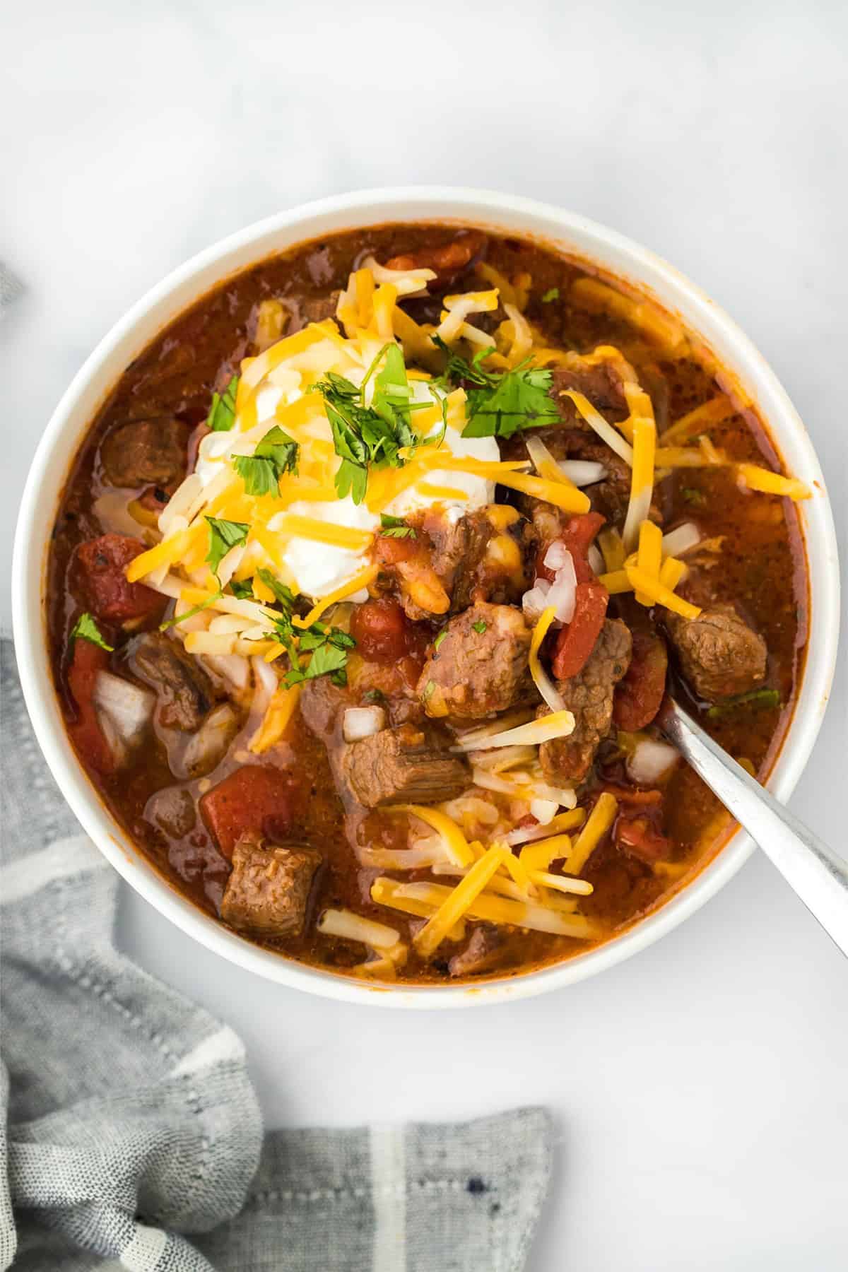 Overhead shot of a bowl of brisket chili topped with shredded cheese, sour cream, and cilantro