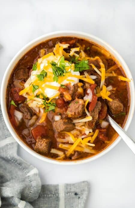 Overhead shot of a bowl of brisket chili topped with shredded cheese, sour cream, and cilantro