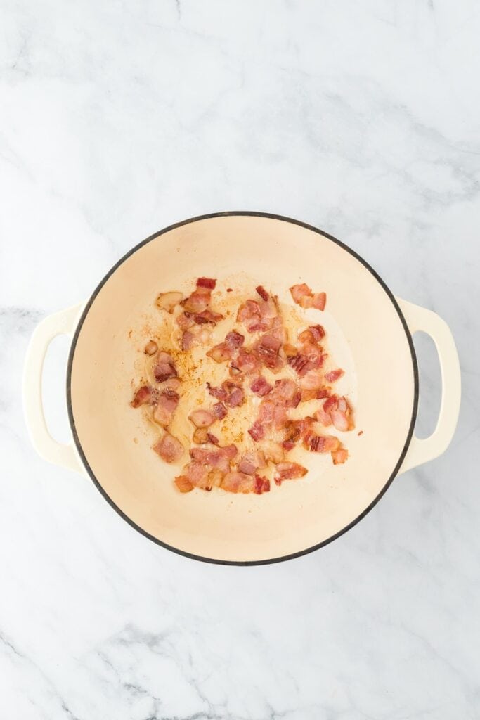Bacon pieces rendered and slightly browned in the Dutch oven