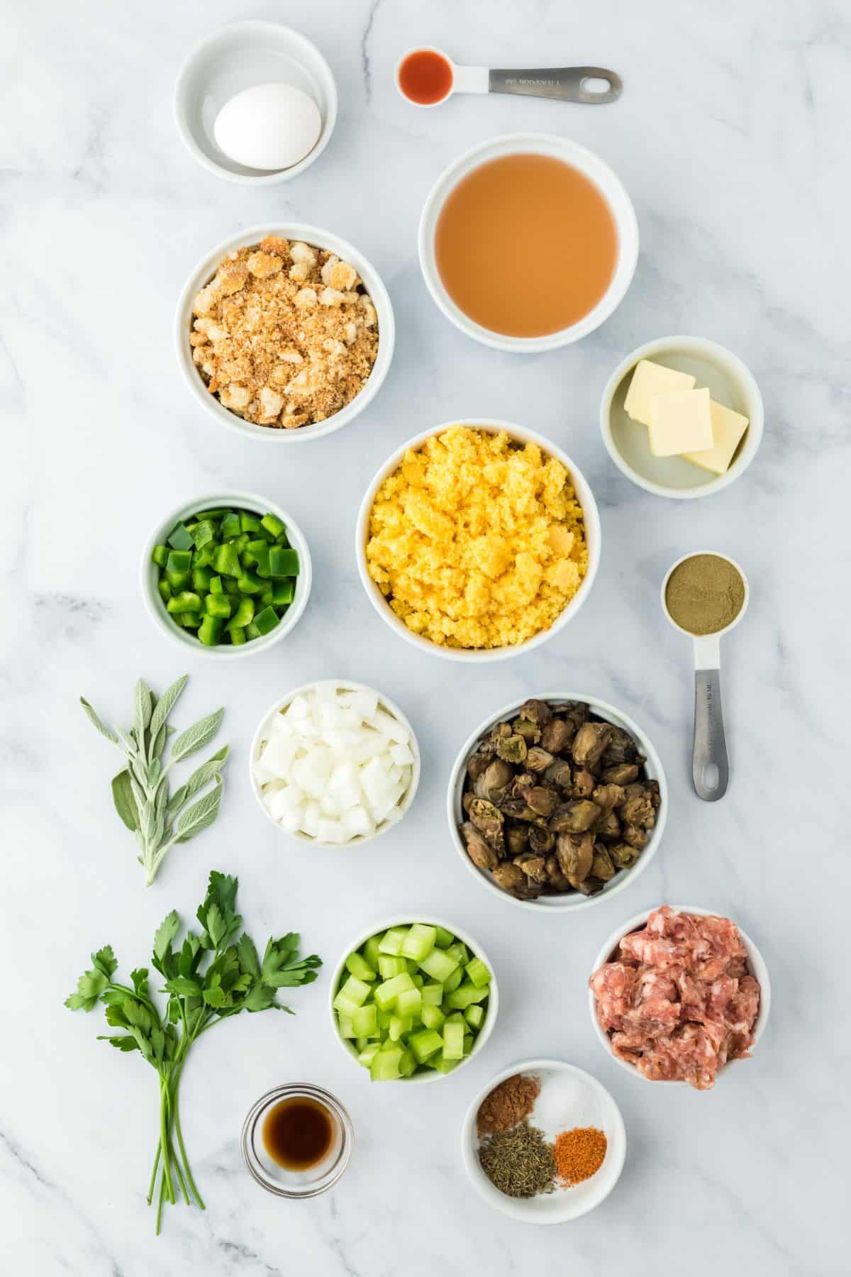 Overhead shot of ingredients to make oyster dressing on a white surface before baking