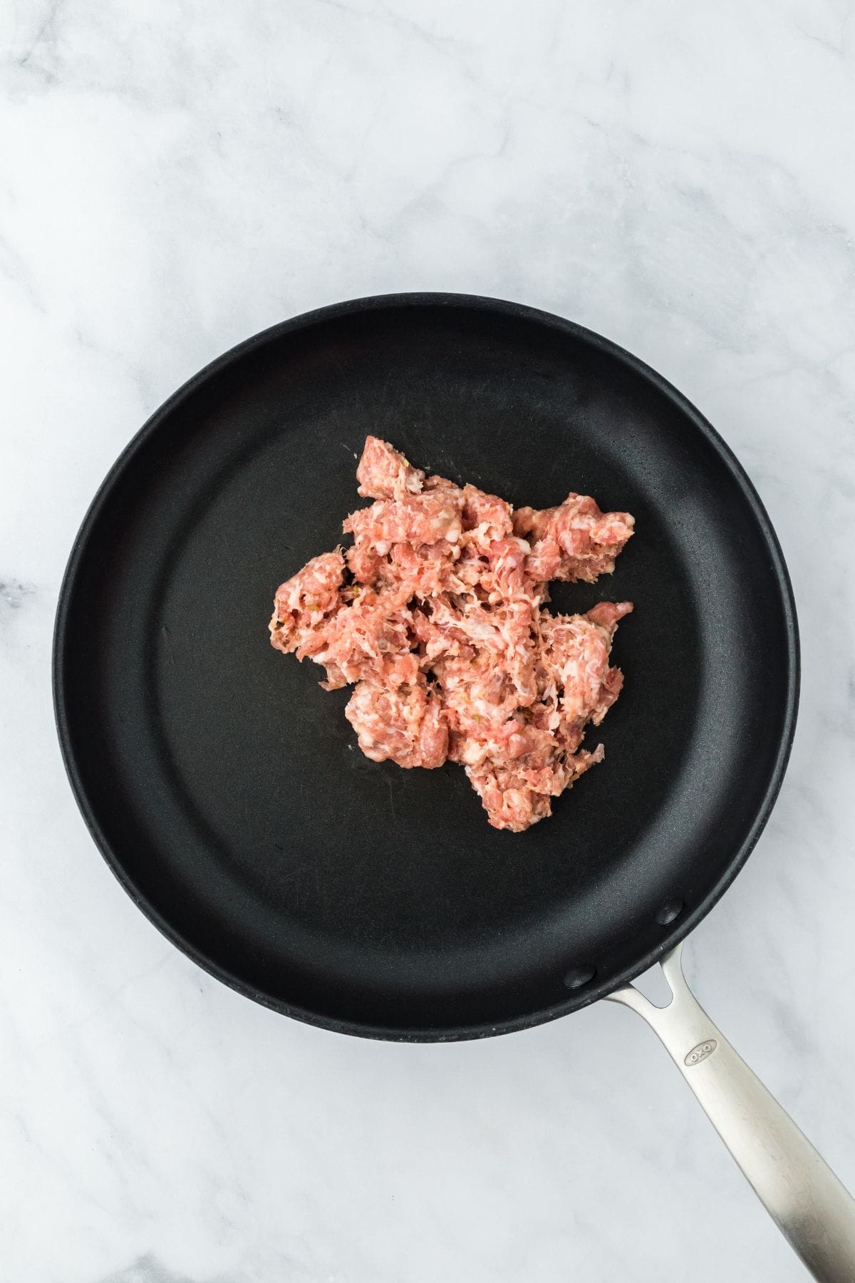 Raw ground sausage in a black skillet