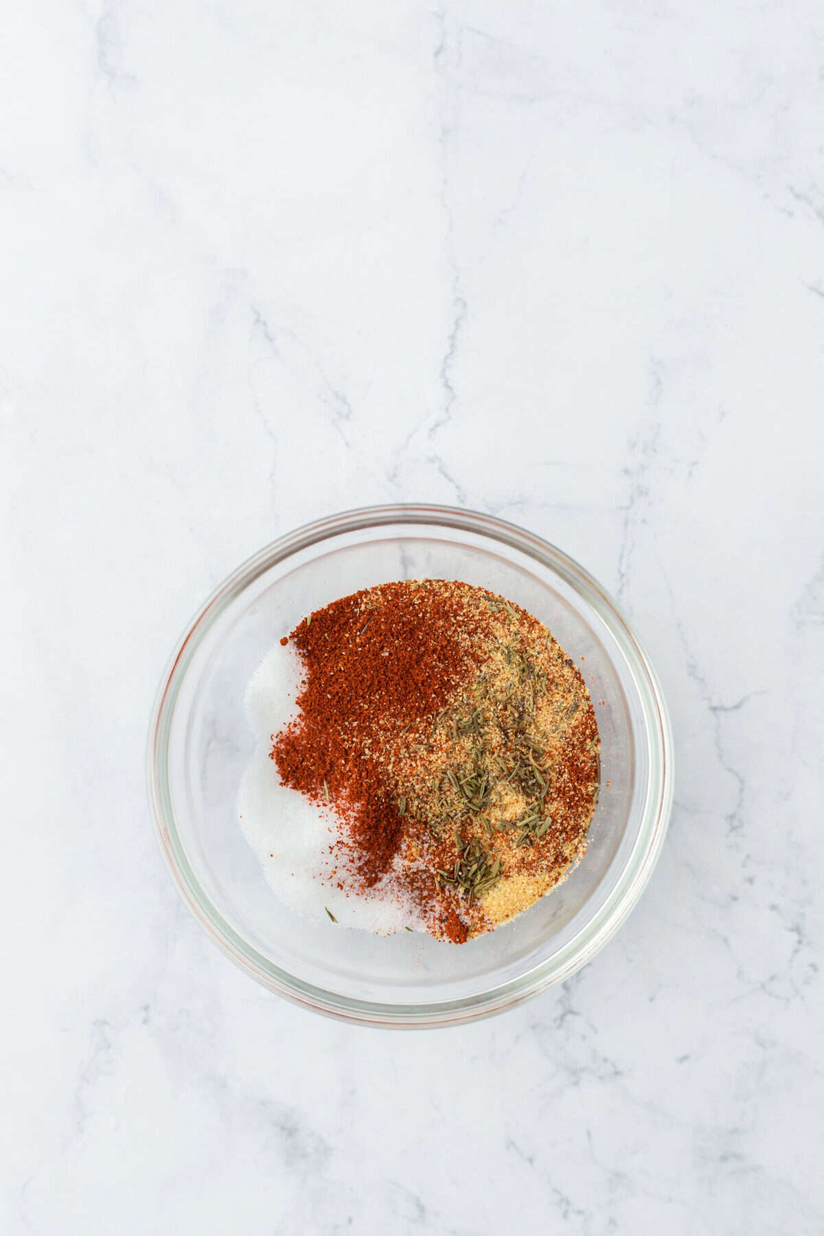 a small clear bowl with seasonings shown before stirring to coat the pork chops