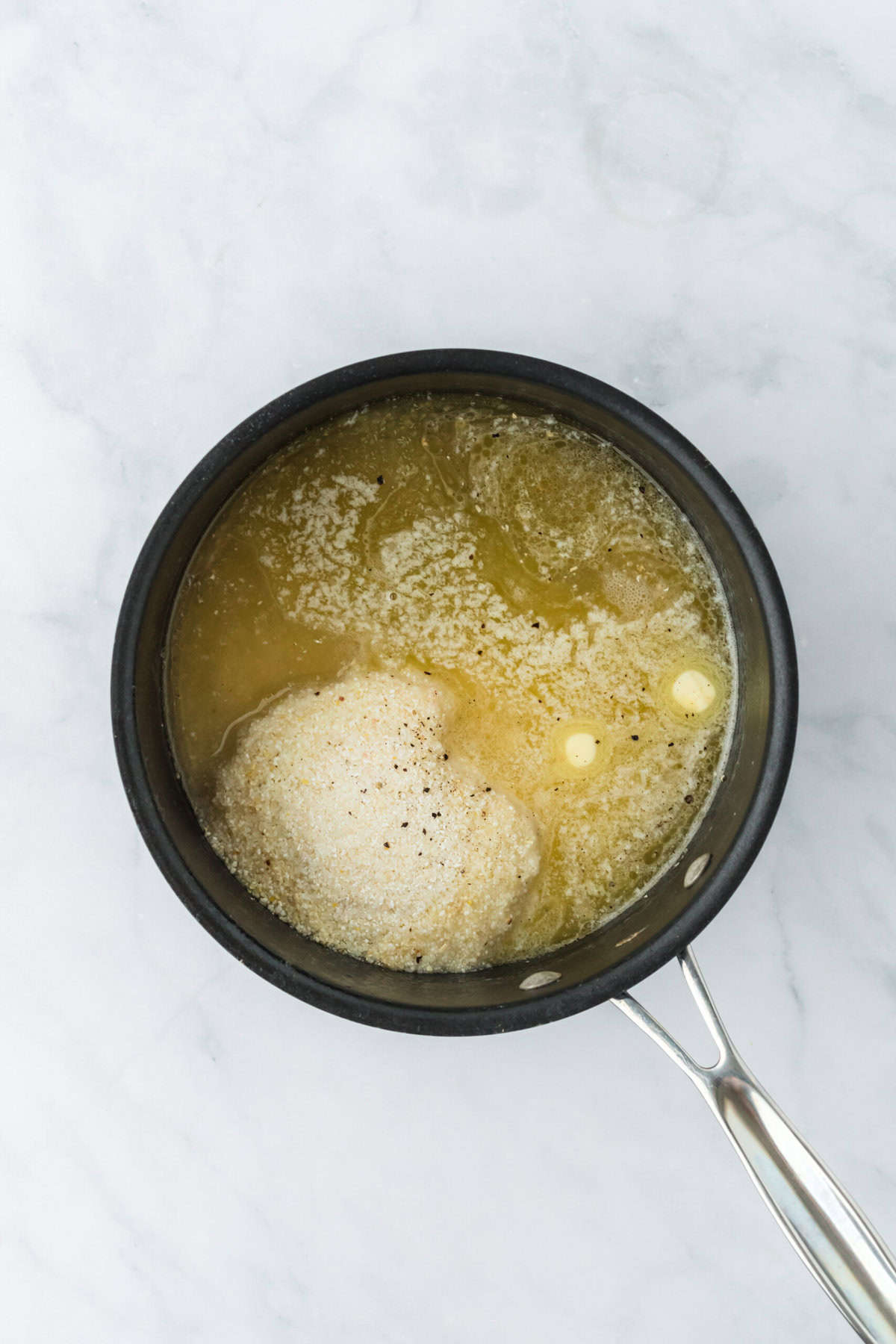 Grits, butter, salt and pepper in a saucepan being cooked together