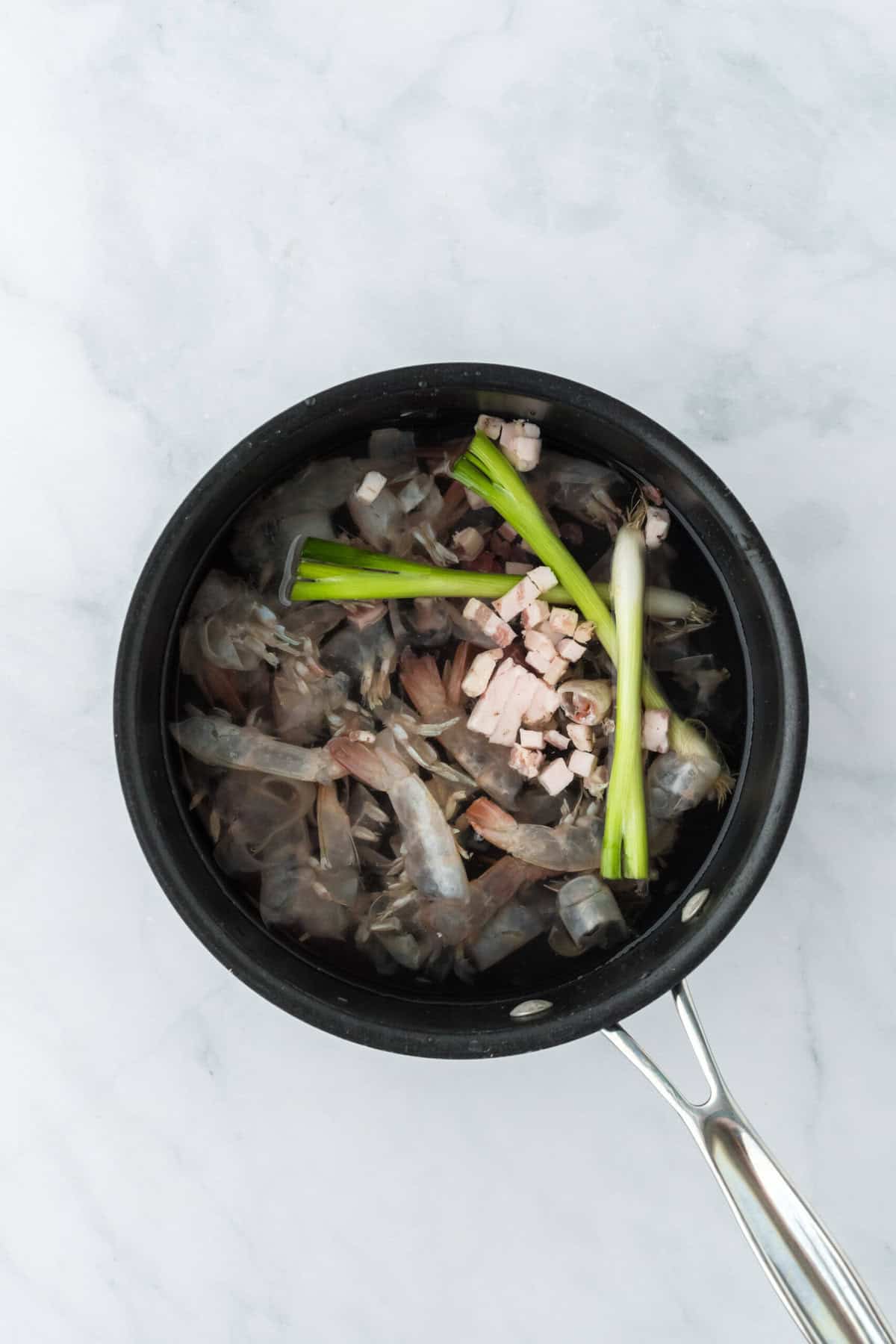 Shrimp stock being made with shrimp shells and onions in water in pot