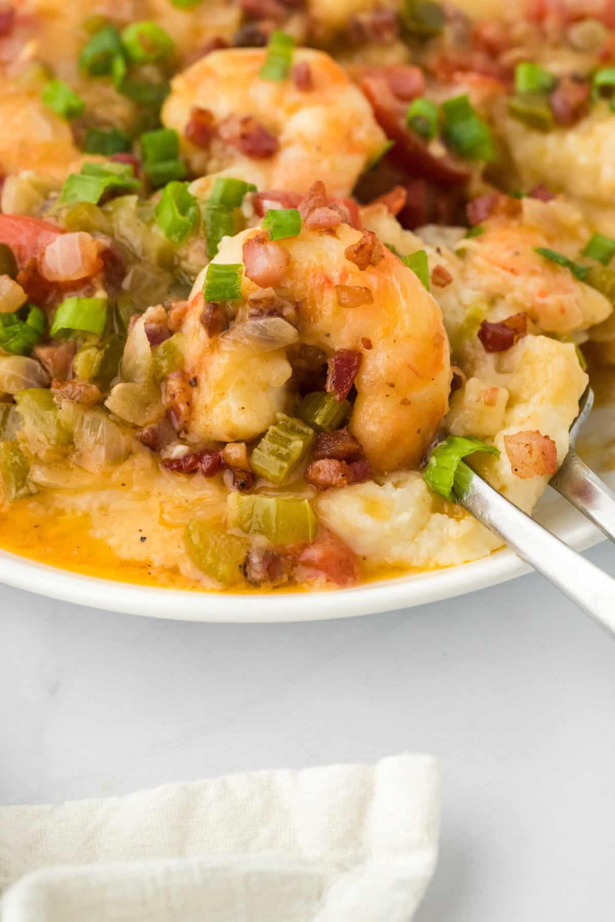 A large bowl of Southern shrimp and grits recipe being eaten on white countertop