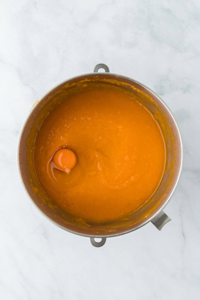 Eggs added to Southern sweet potato pie filling in stand mixer on white countertop