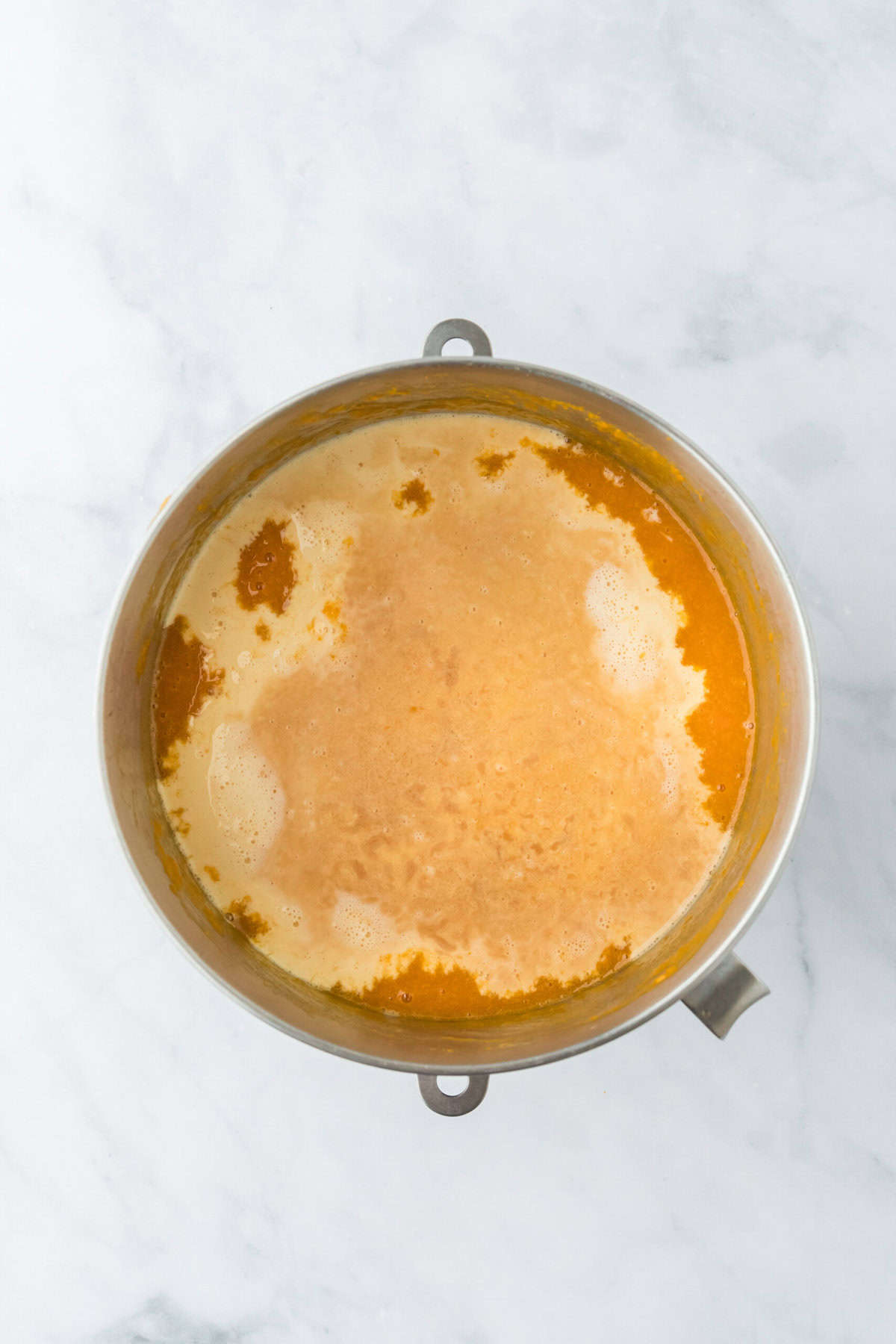 Evaporated milk and vanilla added to potato pie filling on white countertop