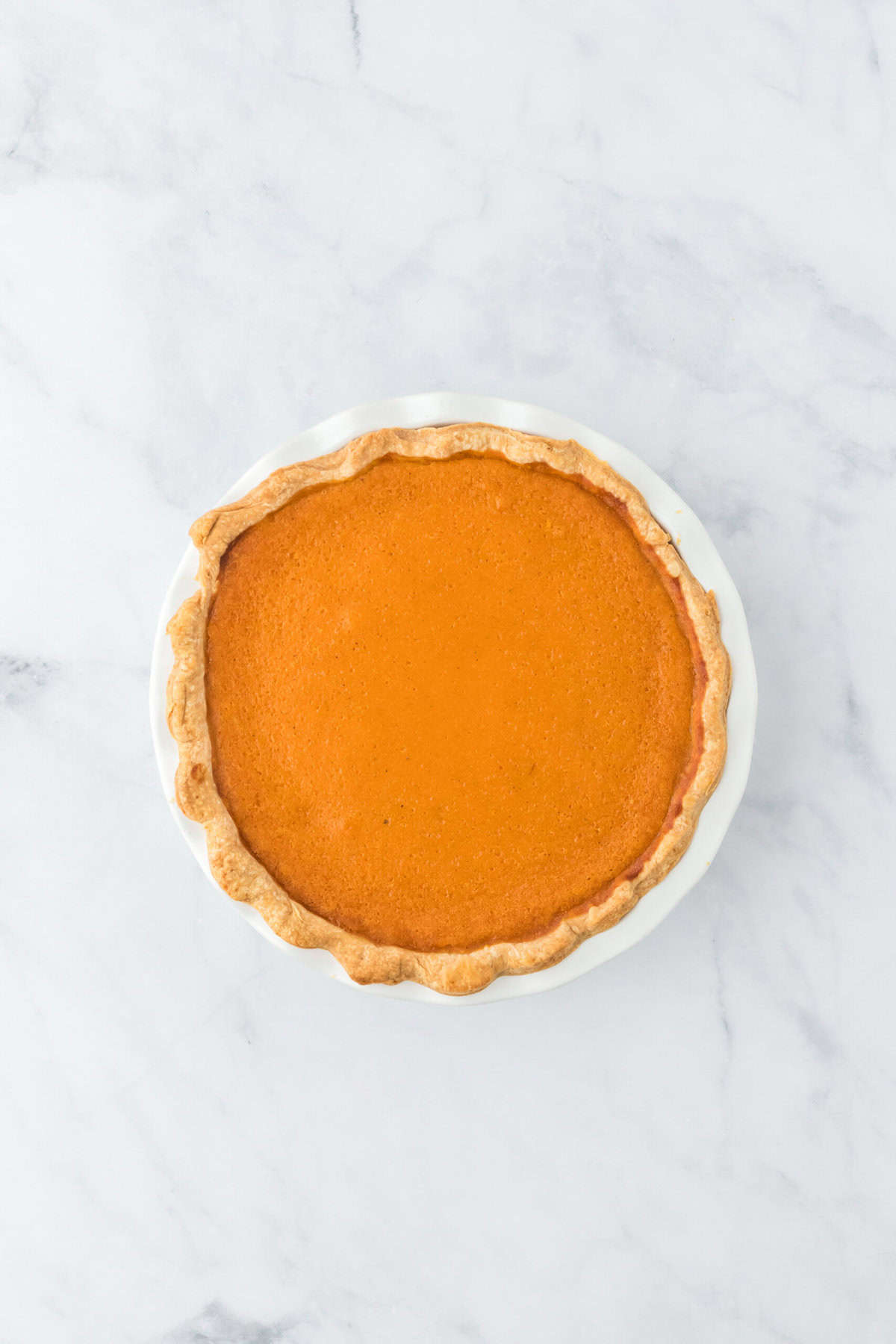 Baked sweet potato pie recipe on white countertop out of the oven