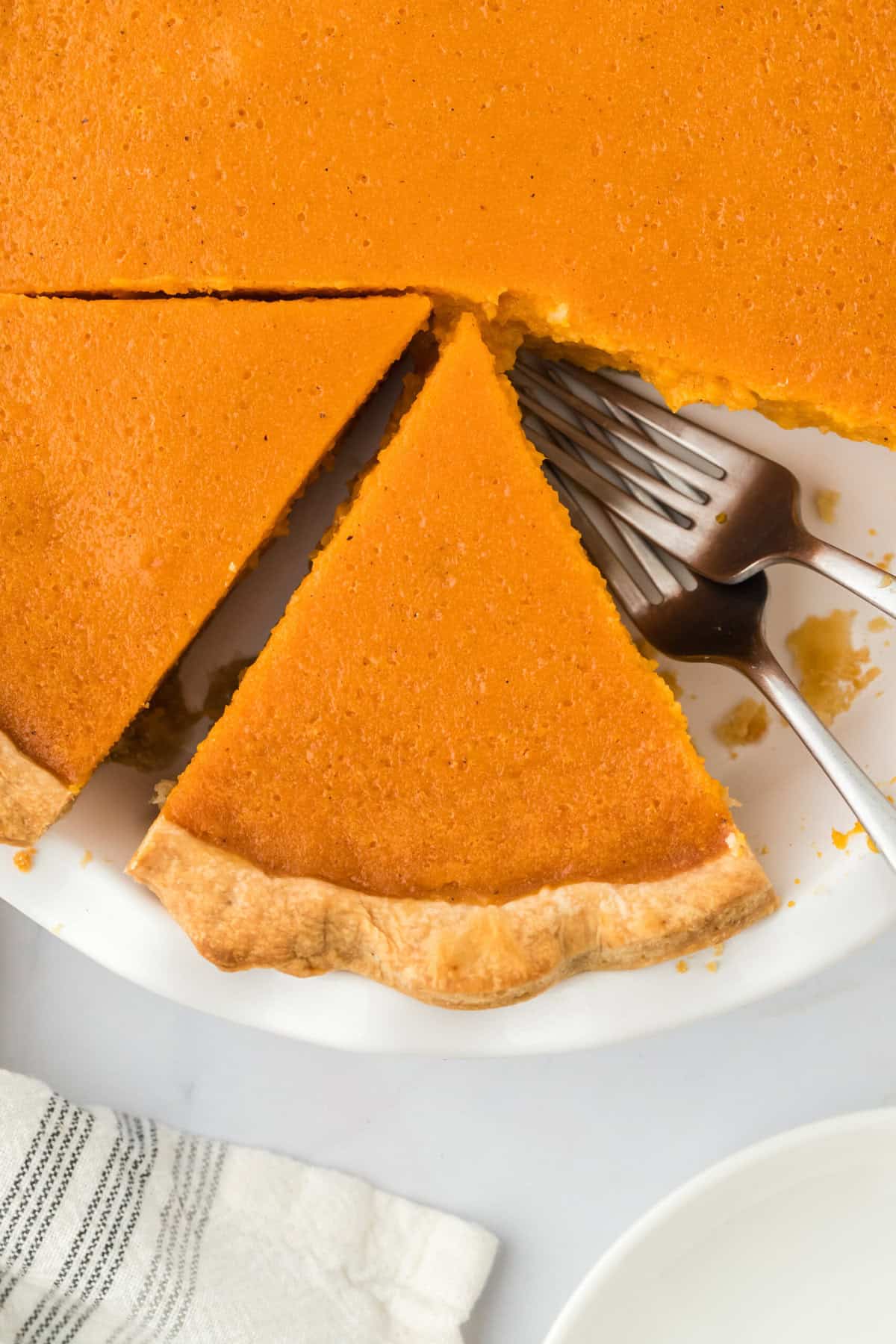 An overhead of Southern potato pie cut into on a white countertop with striped napkin.