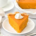 A slice of Southern sweet potato pie recipe on a white plate with full pie in the white background
