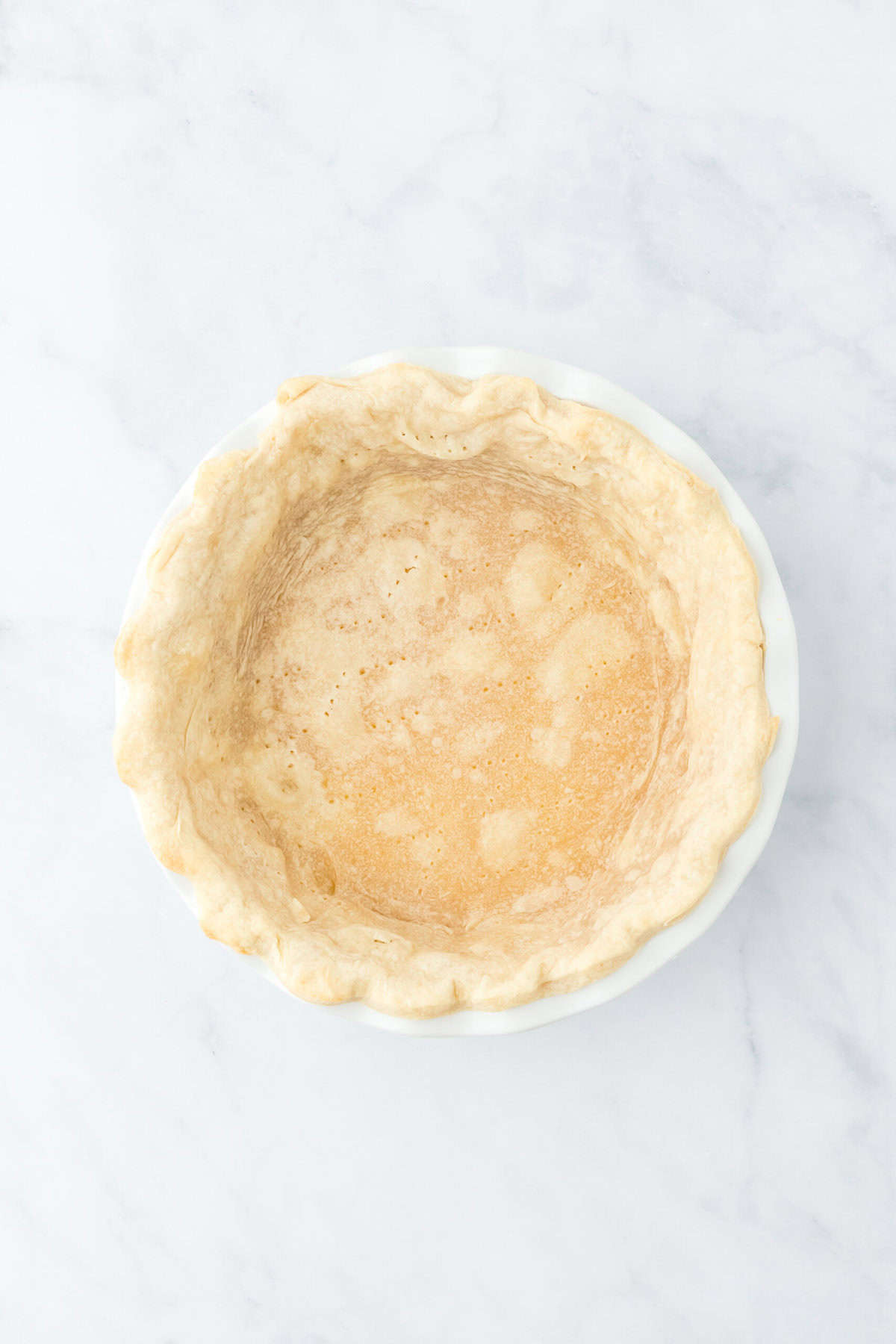 Prebaked pie crust on a white countertop