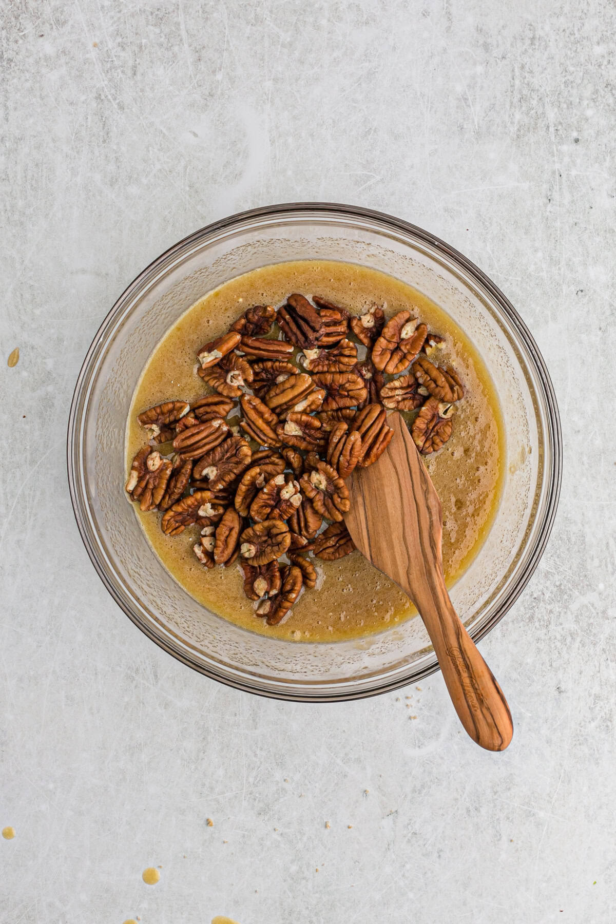 Pecan halves added to glass bowl with filling
