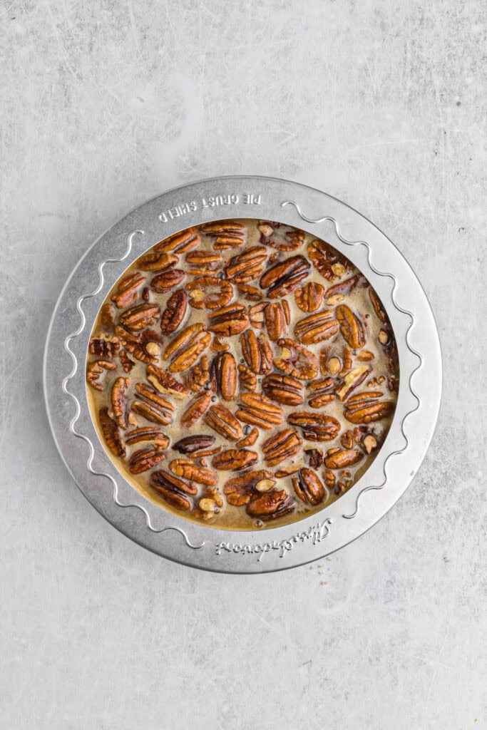 Pecan pie before baking with pie shield on outside