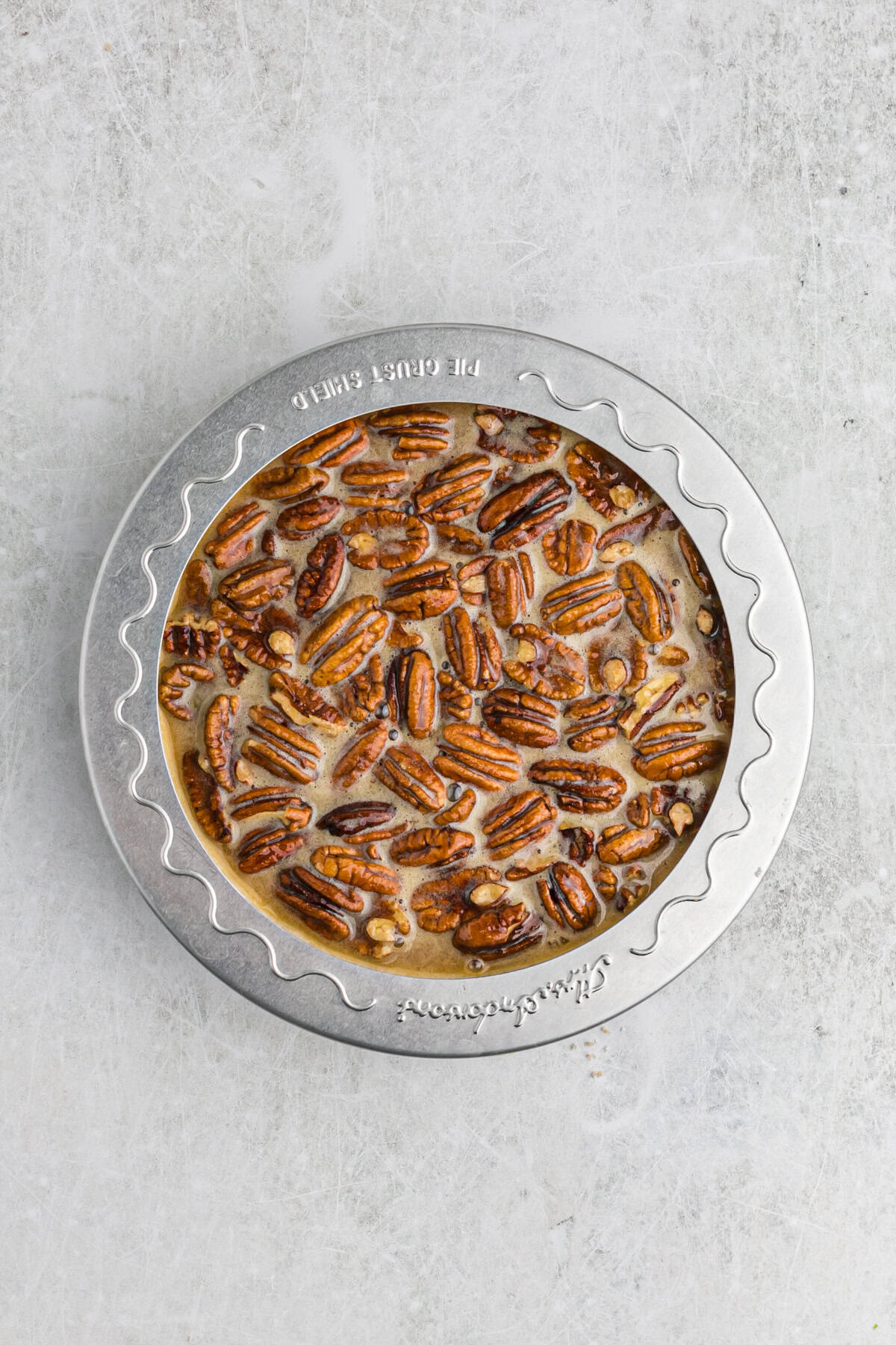 Pecan pie before baking with pie shield on outside
