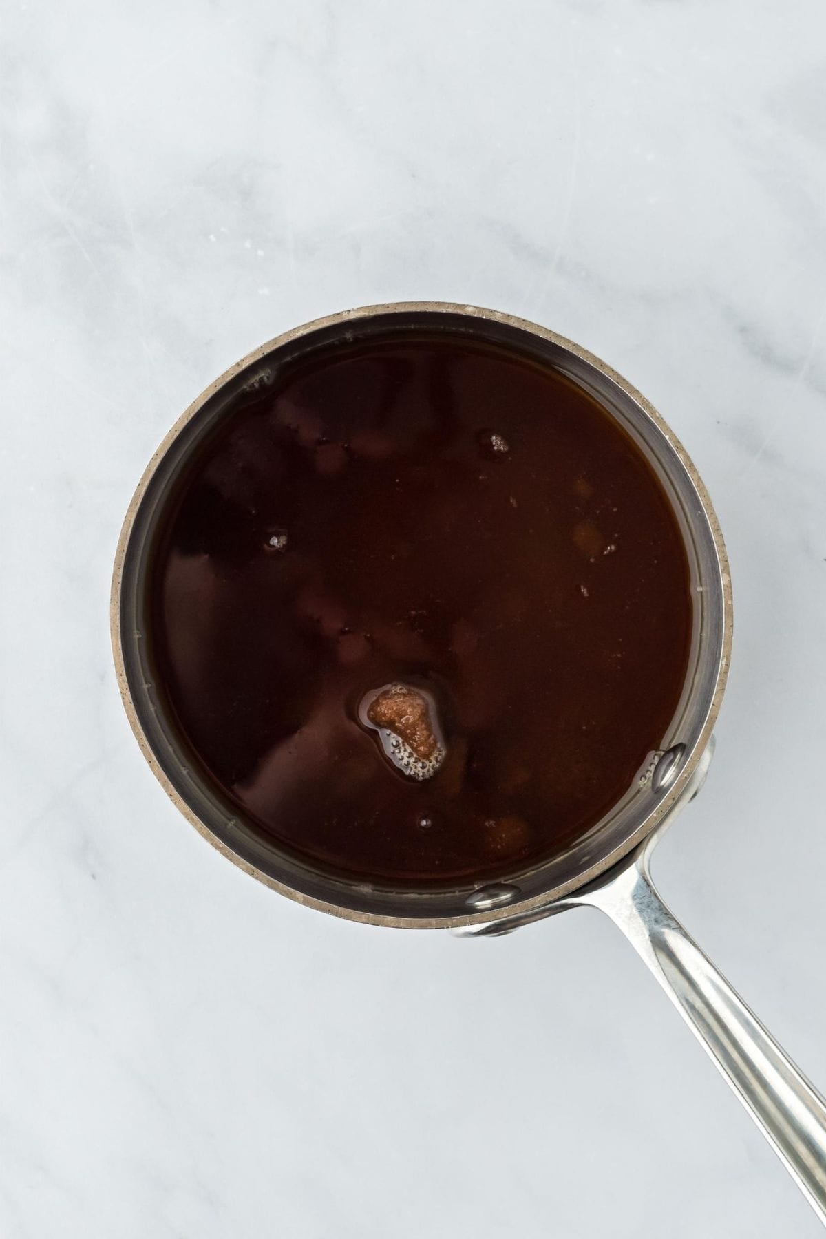 A saucepan filled with the base of the sauce for the apple fritter bread pudding.