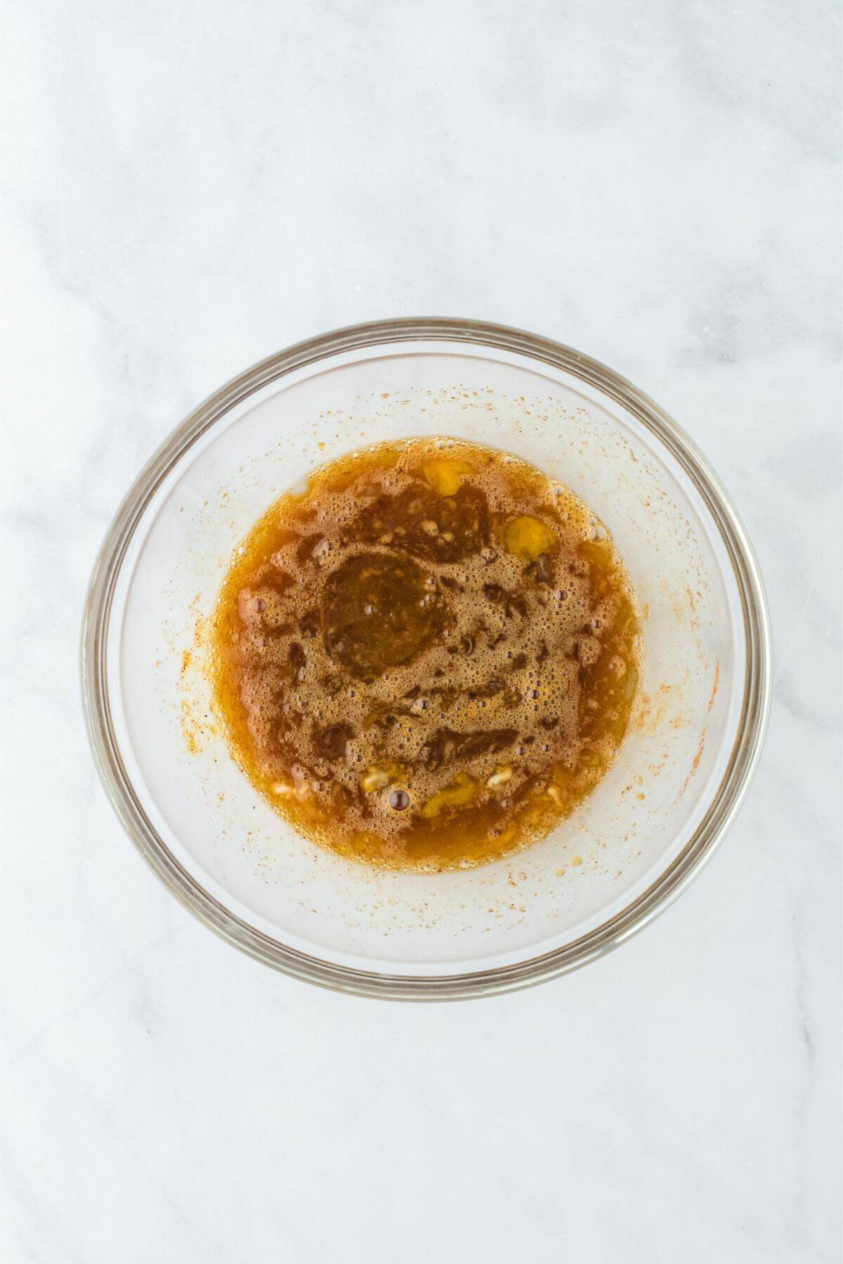 Mixed egg, sugar, and spice mixture in a clear bowl.