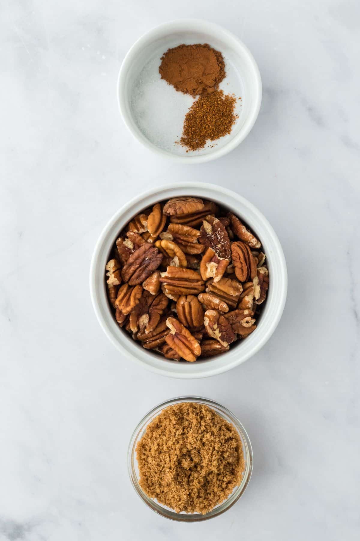 Overhead shot of ingredients for making candied pecans on a marble surface before cooking