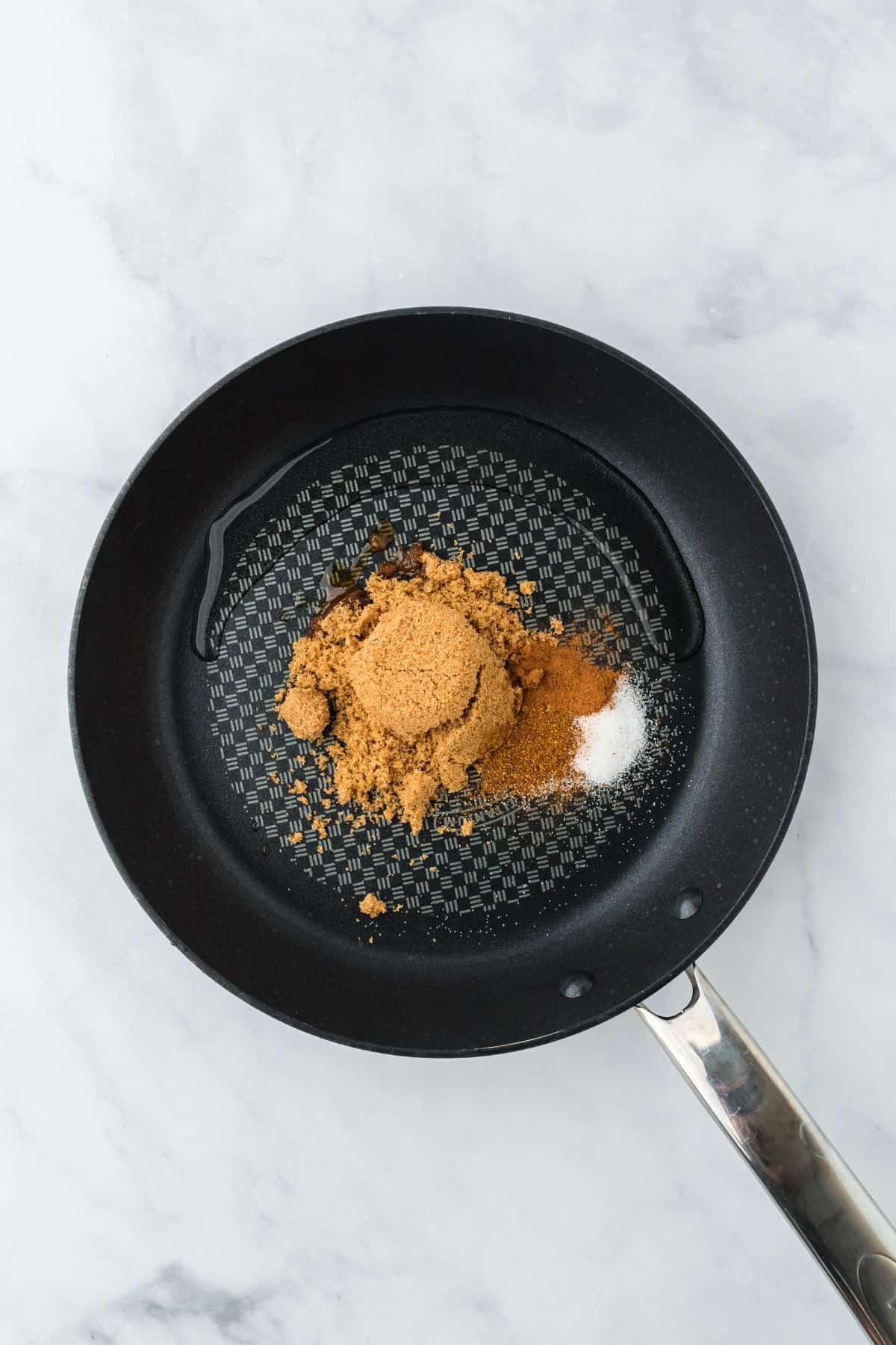 Overhead view of a frying pan with brown sugar, cinnamon, and salt