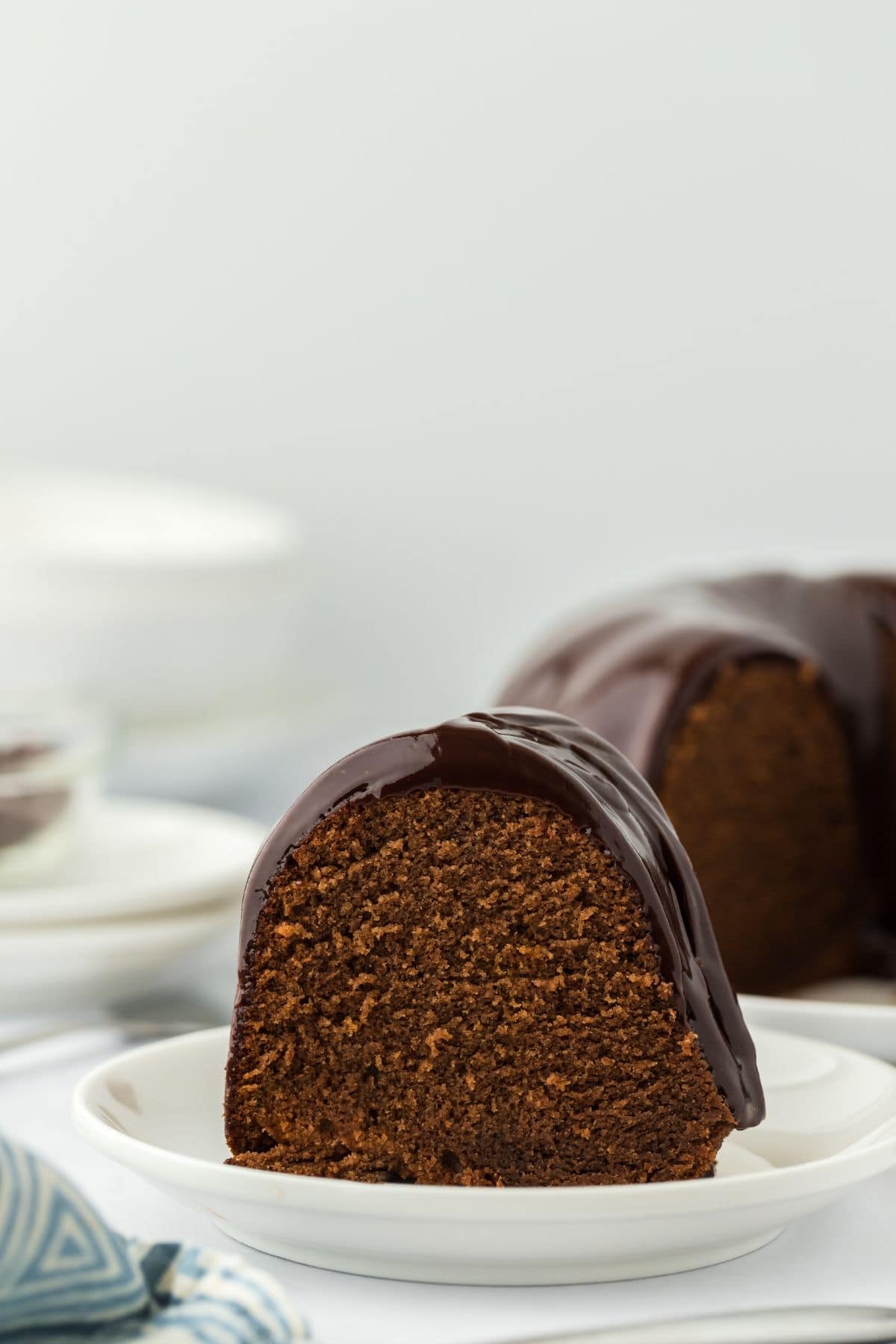 A close-up shot of a chocolate pound cake slice showing its moist crumb, covered in glossy chocolate glaze