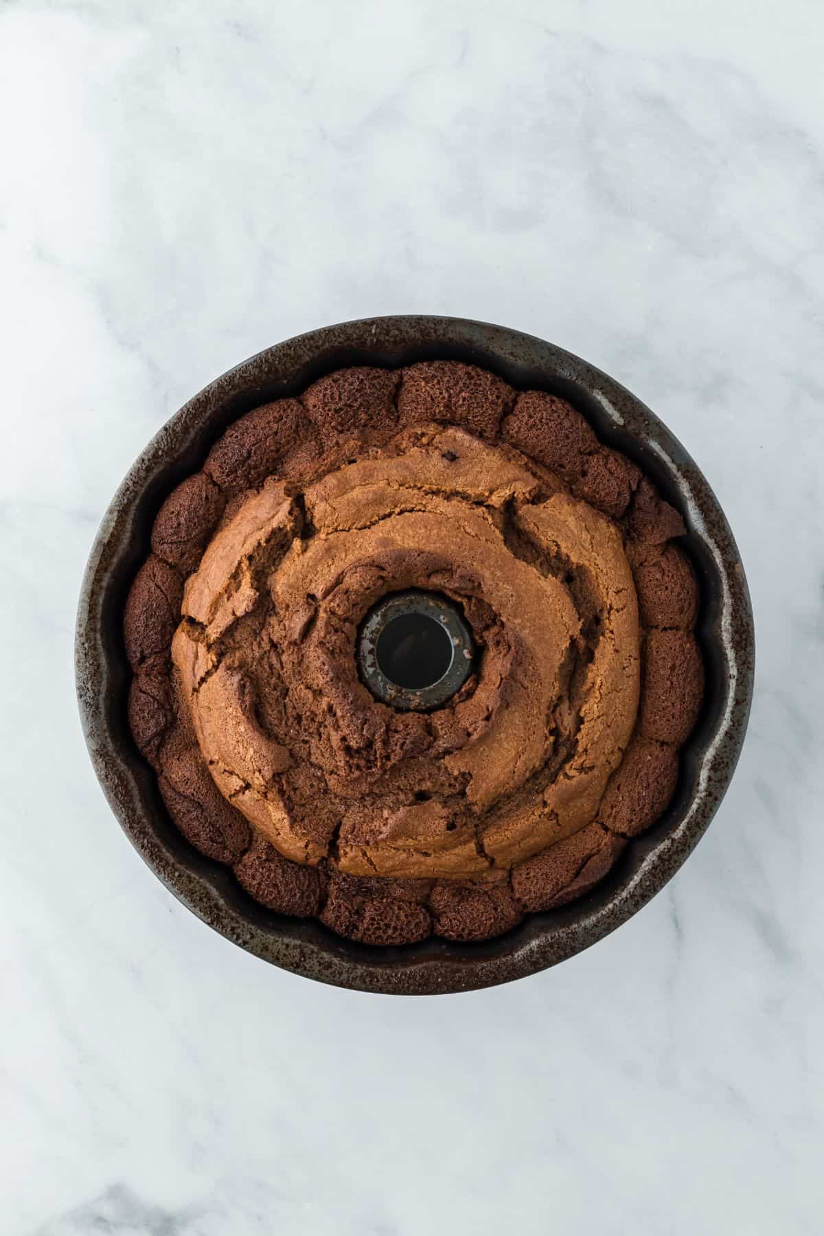 Freshly baked chocolate pound cake in the bundt pan, showing a golden-brown, cracked top