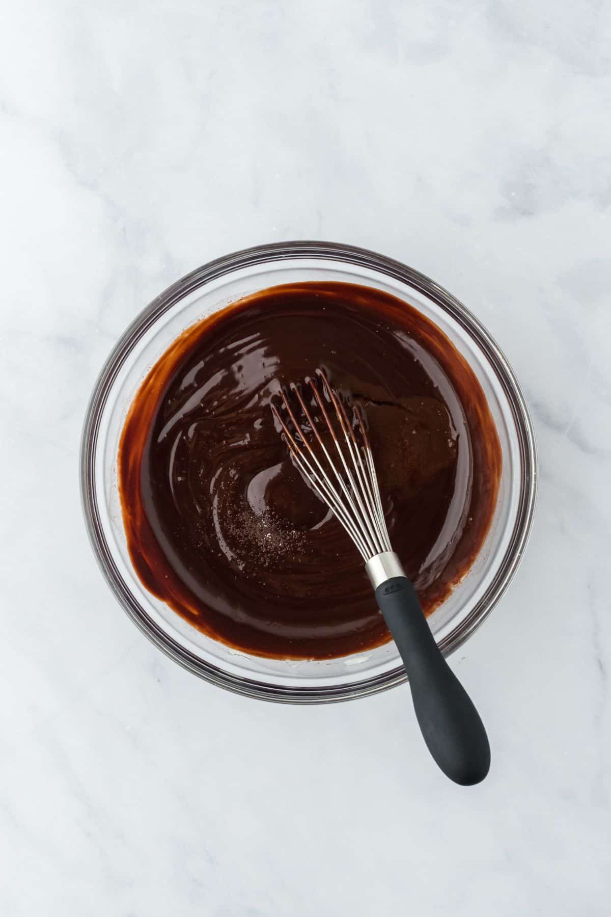 Smooth, glossy chocolate glaze being whisked in a bowl