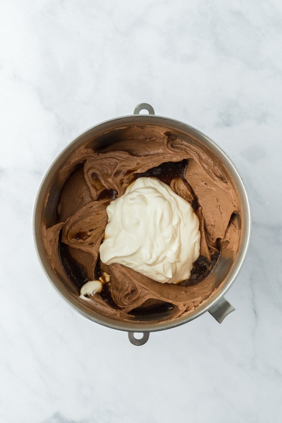 Chocolate pound cake batter in a mixing bowl with a large dollop of sour cream, coffee and vanilla extract on top