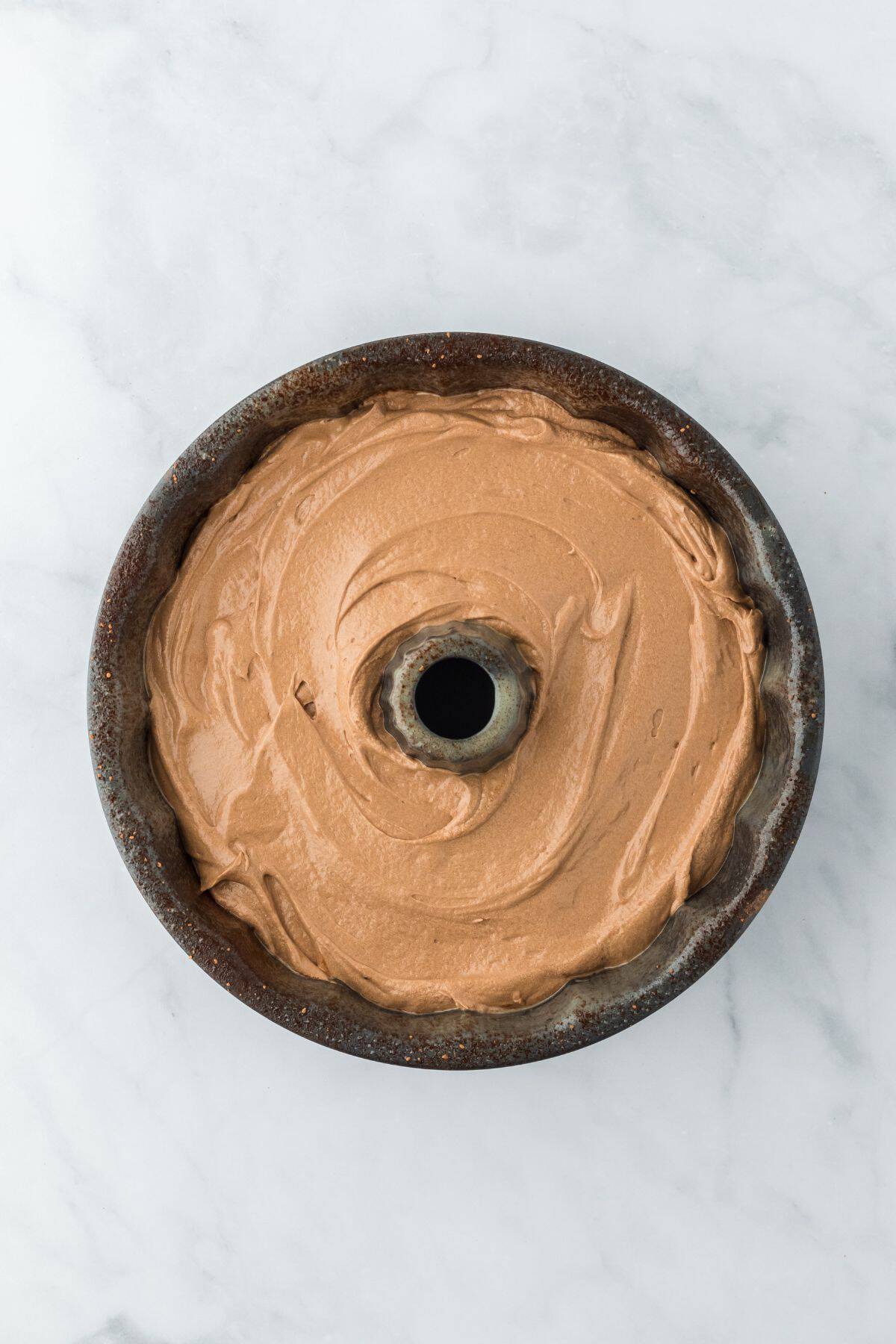 Chocolate pound cake batter evenly spread in a bundt pan, ready for baking